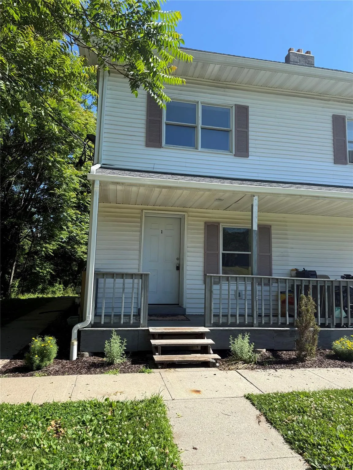 Two-story residence featuring white vinyl siding and a covered front porch Two-story residence featuring white vinyl siding and a covered front porch