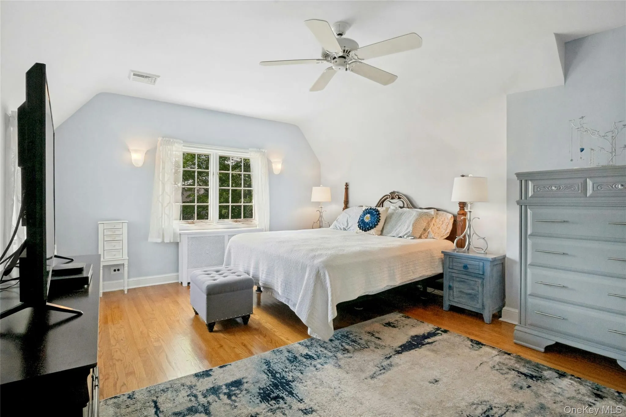Hardwood flooring throughout featuring a ceiling fan, sconce lighting, and a multi-pane window Hardwood flooring throughout featuring a ceiling fan, sconce lighting, and a multi-pane window