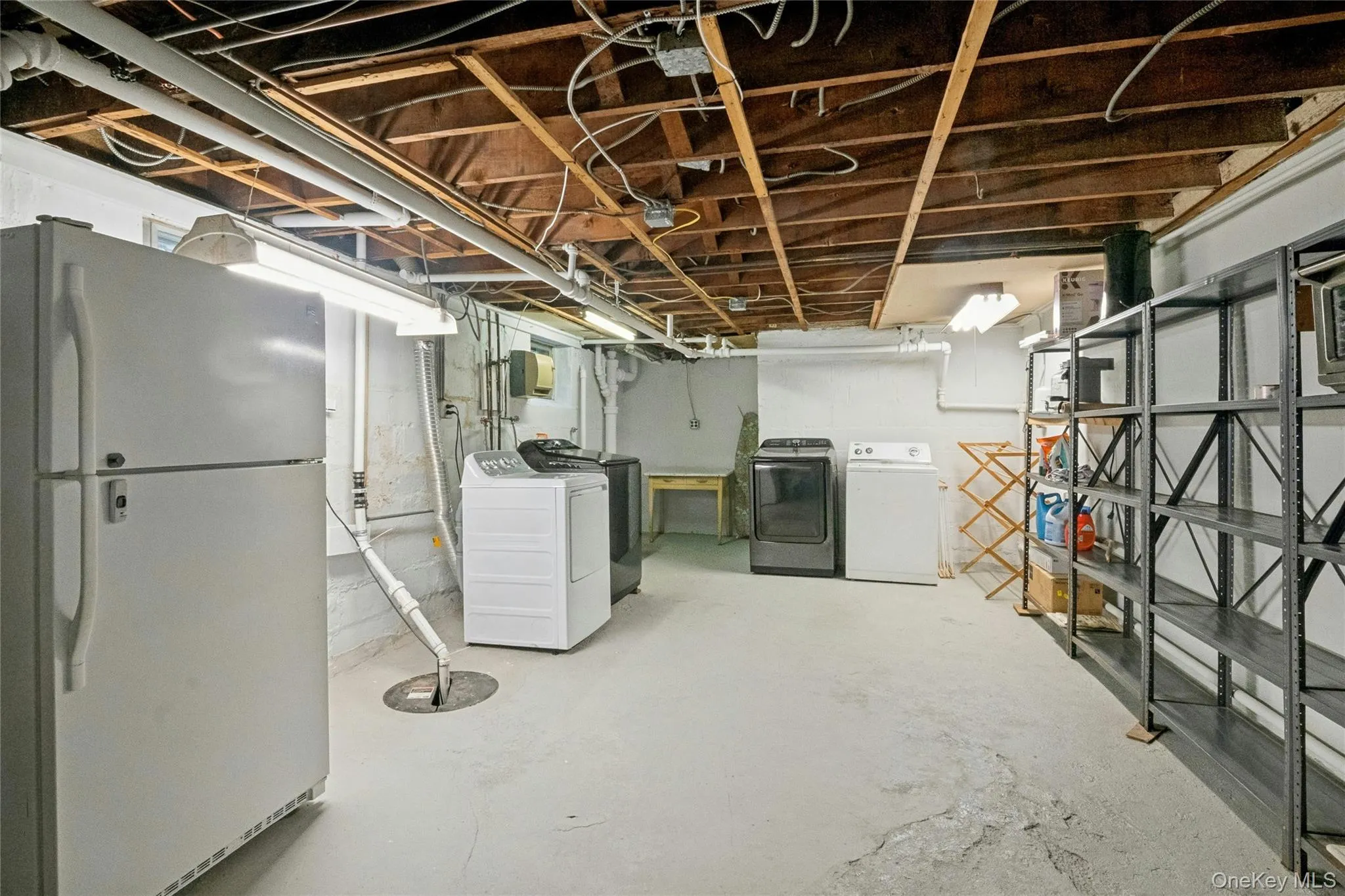 Unfinished basement space featuring exposed wood joists and concrete flooring Unfinished basement space featuring exposed wood joists and concrete flooring
