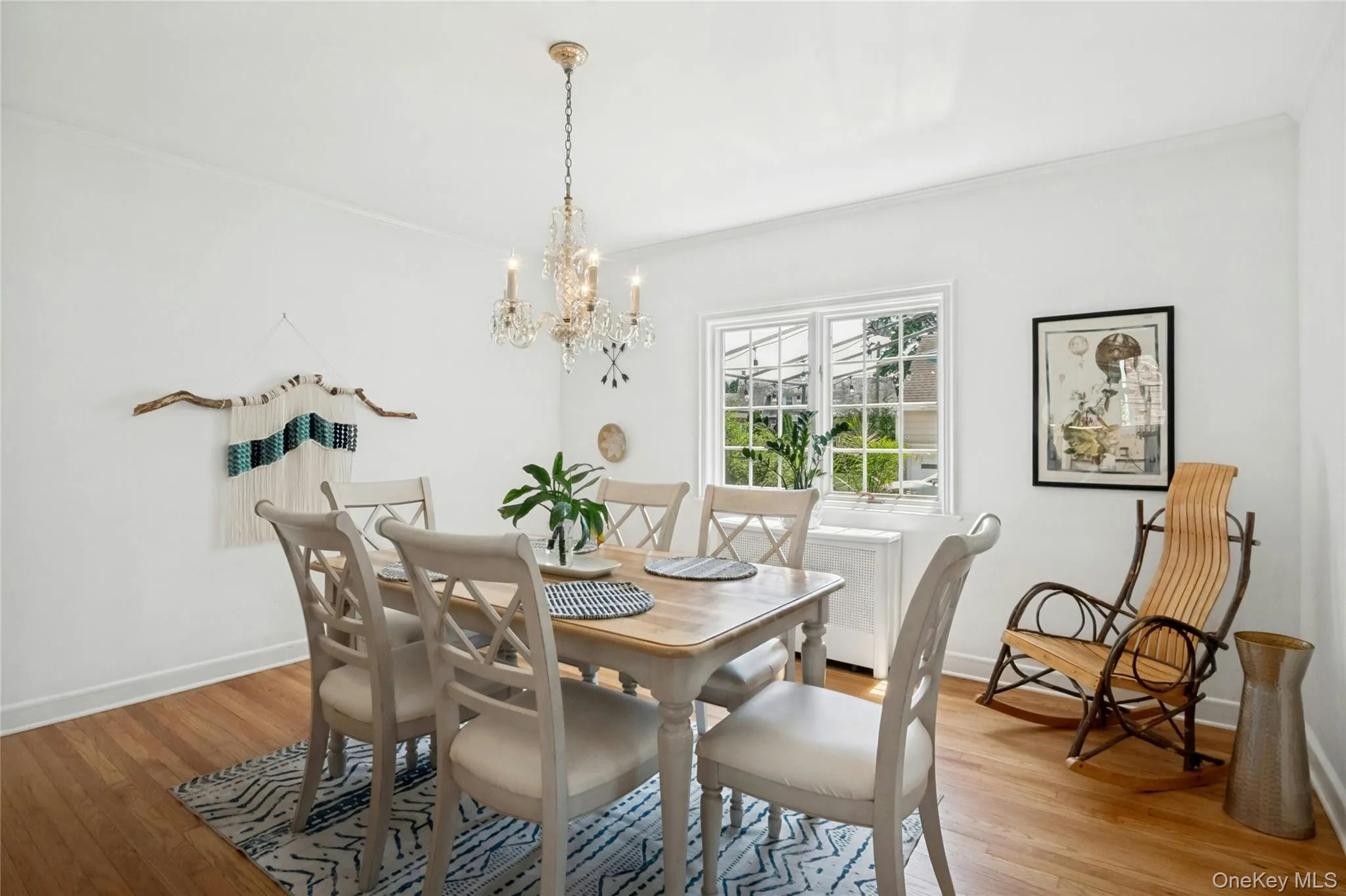 Dining area featuring wood-finish flooring, white painted walls, and a crystal chandelier Dining area featuring wood-finish flooring, white painted walls, and a crystal chandelier