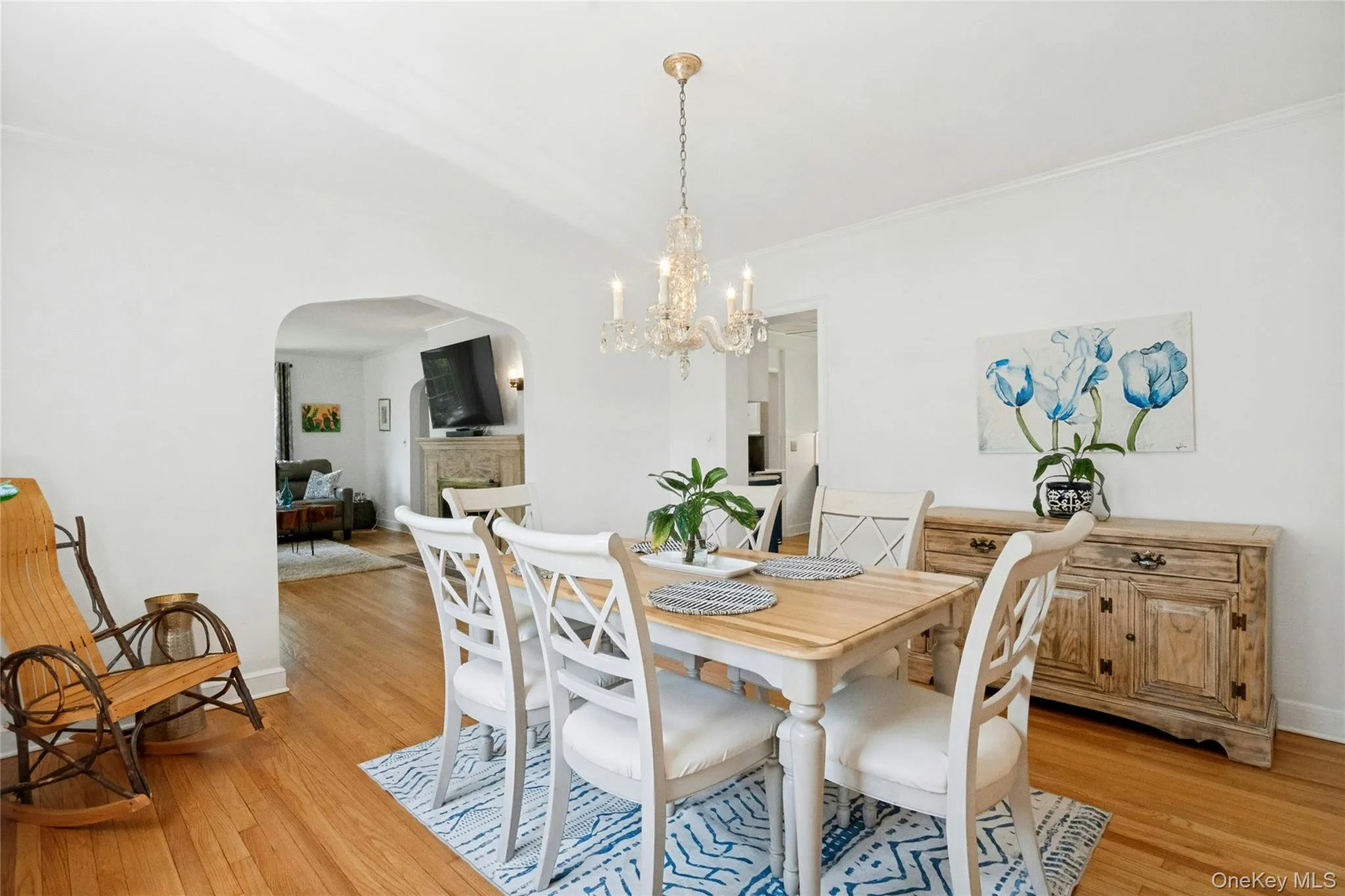 Dining area featuring wood-finish flooring, a crystal chandelier, and a decorative archway Dining area featuring wood-finish flooring, a crystal chandelier, and a decorative archway