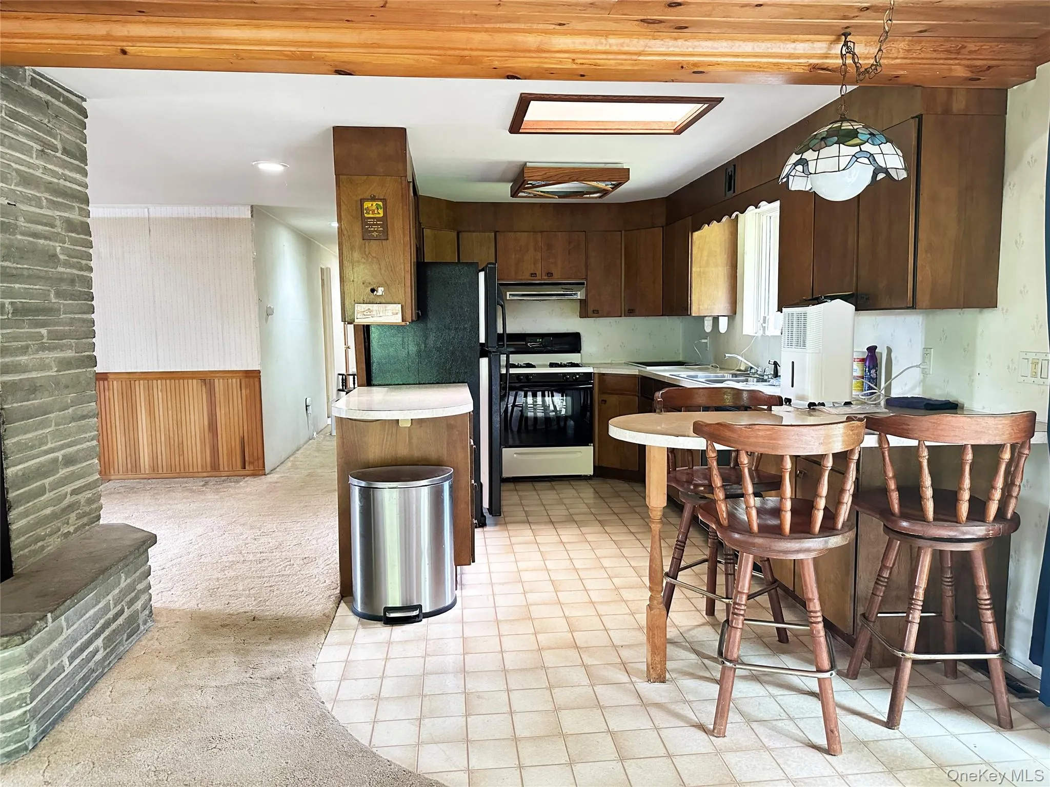 Rustic kitchen and dining area with wood cabinetry, skylights, breakfast seating, and open connection to the main living space. Rustic kitchen and dining area with wood cabinetry, skylights, breakfast seating, and open connection to the main living space.