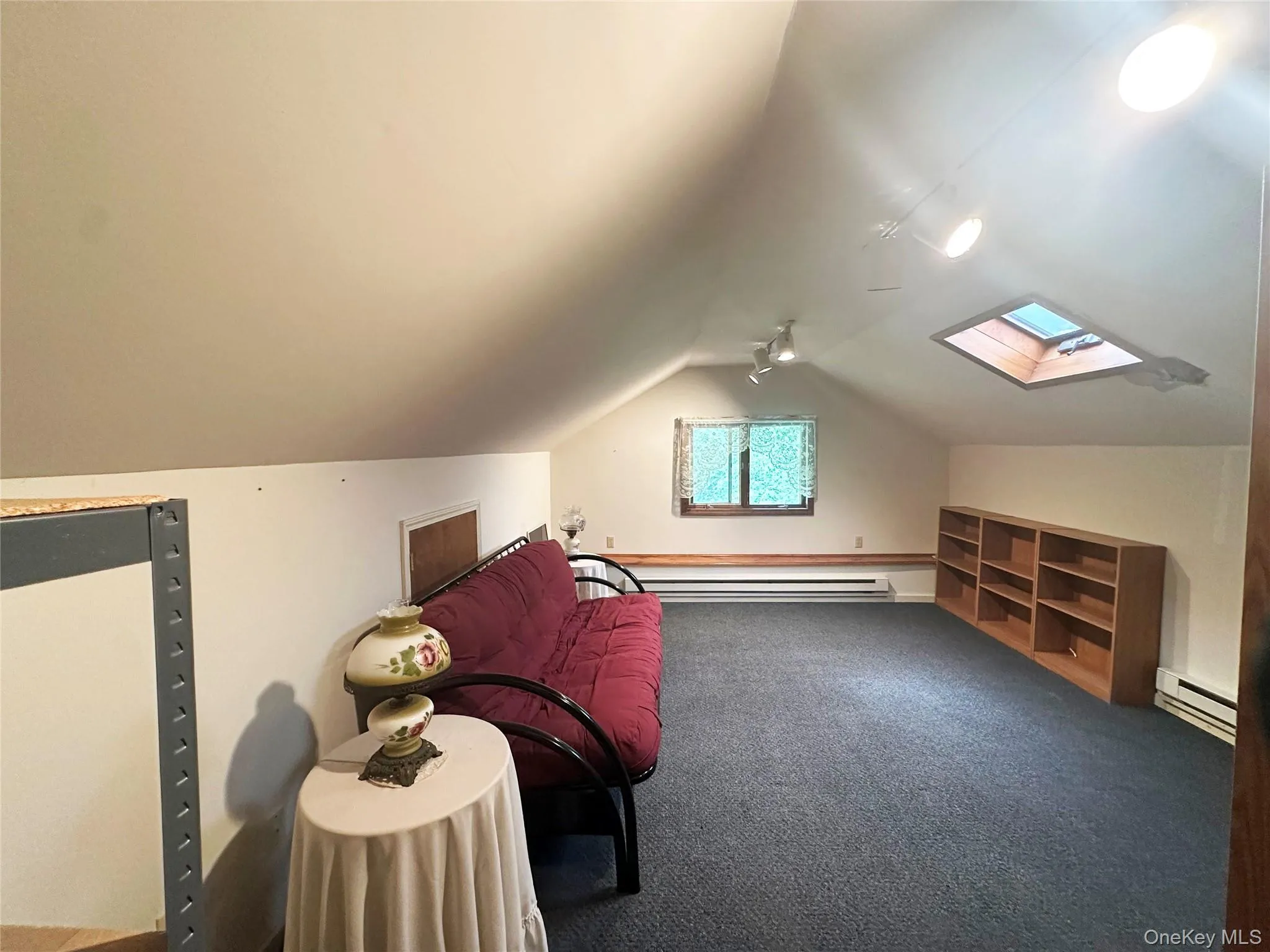 Finished upper-level loft/flex space with skylight, built-in shelving, and potential for office, recreation, or guest overflow use. Finished upper-level loft/flex space with skylight, built-in shelving, and potential for office, recreation, or guest overflow use.