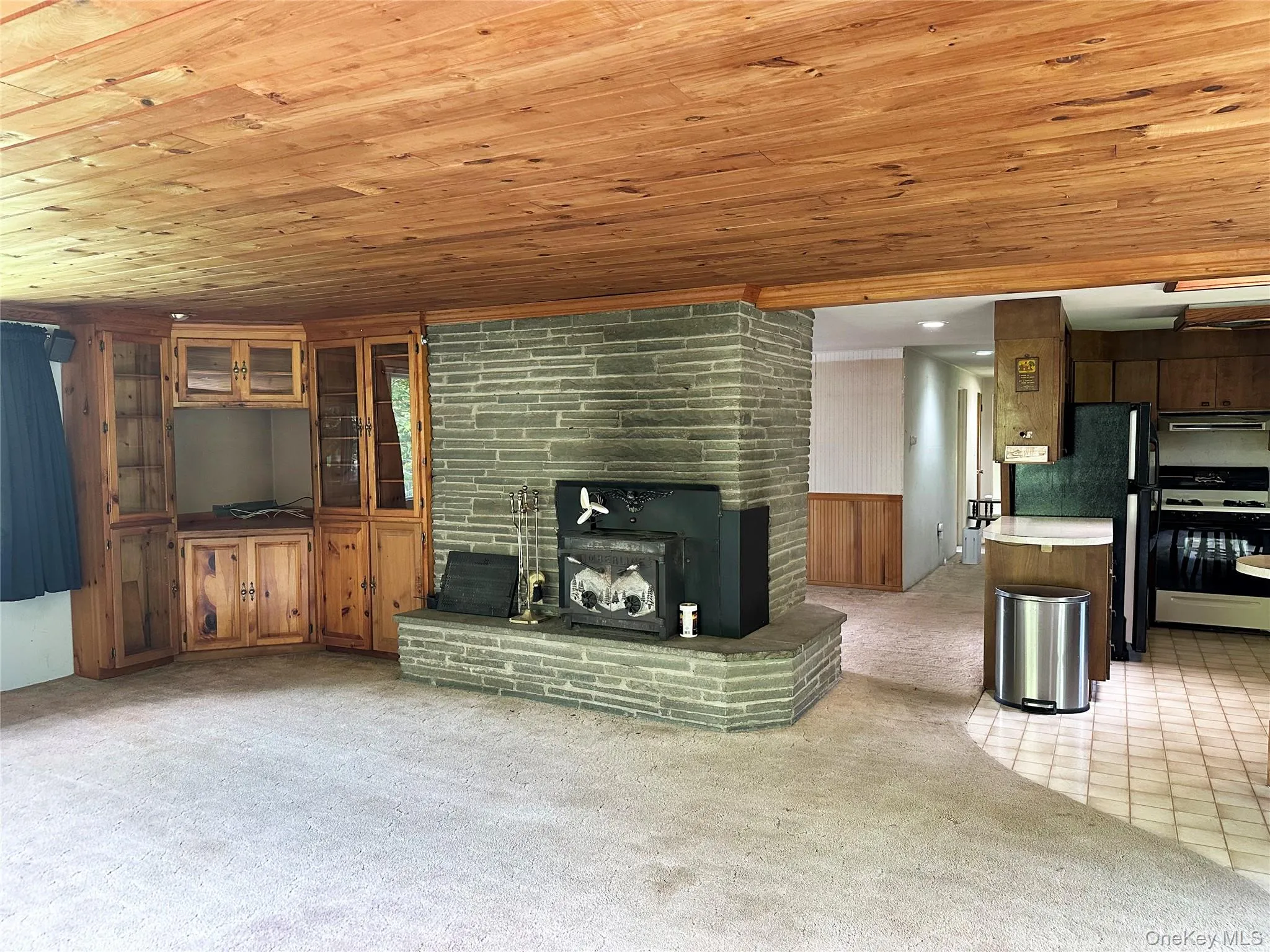 Alternate view of the living area highlighting the open layout, rustic finishes, built-ins, and distinctive stone fireplace centerpiece. Alternate view of the living area highlighting the open layout, rustic finishes, built-ins, and distinctive stone fireplace centerpiece.