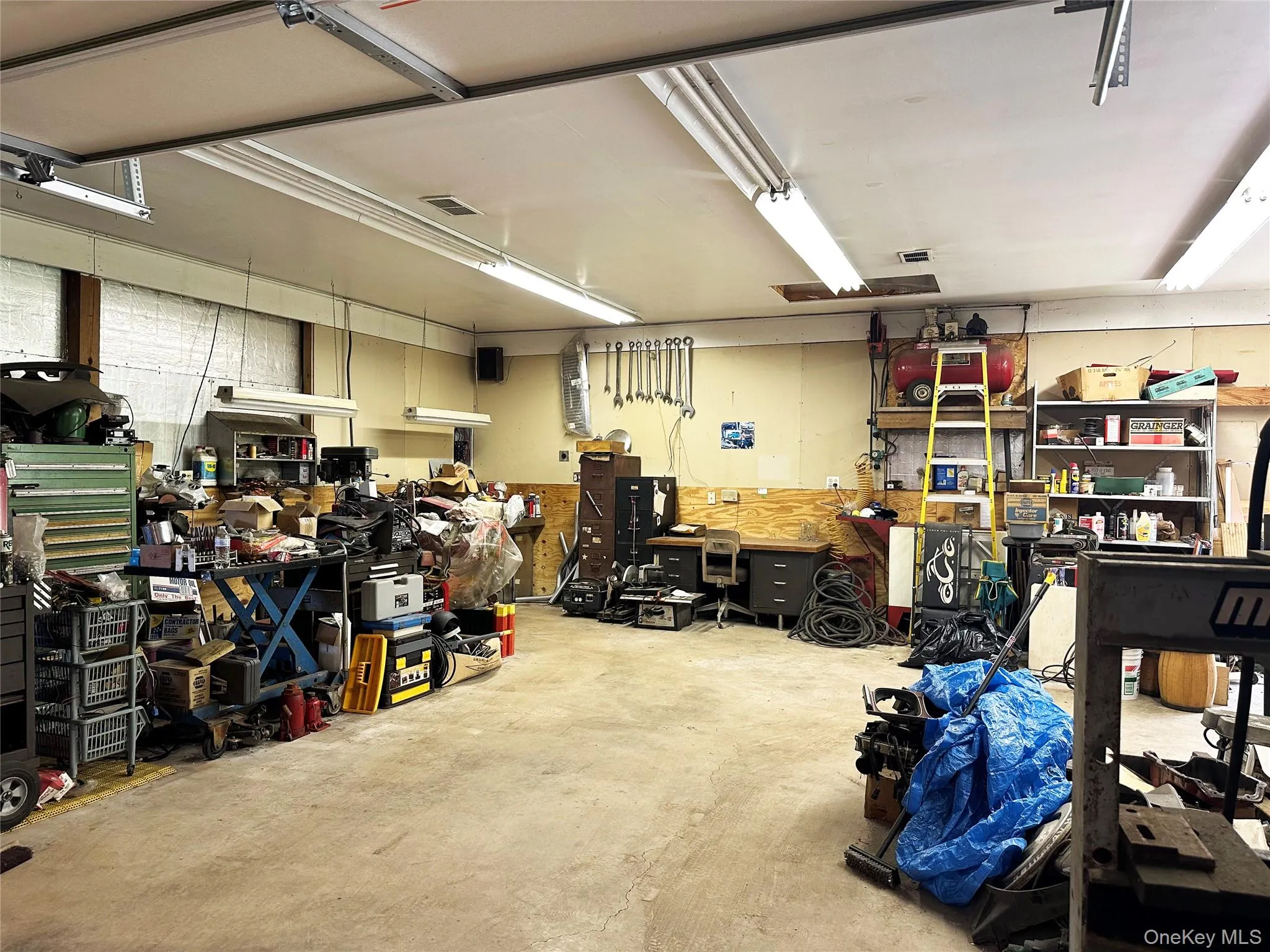 Heated workshop/garage area with concrete floors, utility workspace, and extensive room for tools, machinery, or automotive projects. Heated workshop/garage area with concrete floors, utility workspace, and extensive room for tools, machinery, or automotive projects.