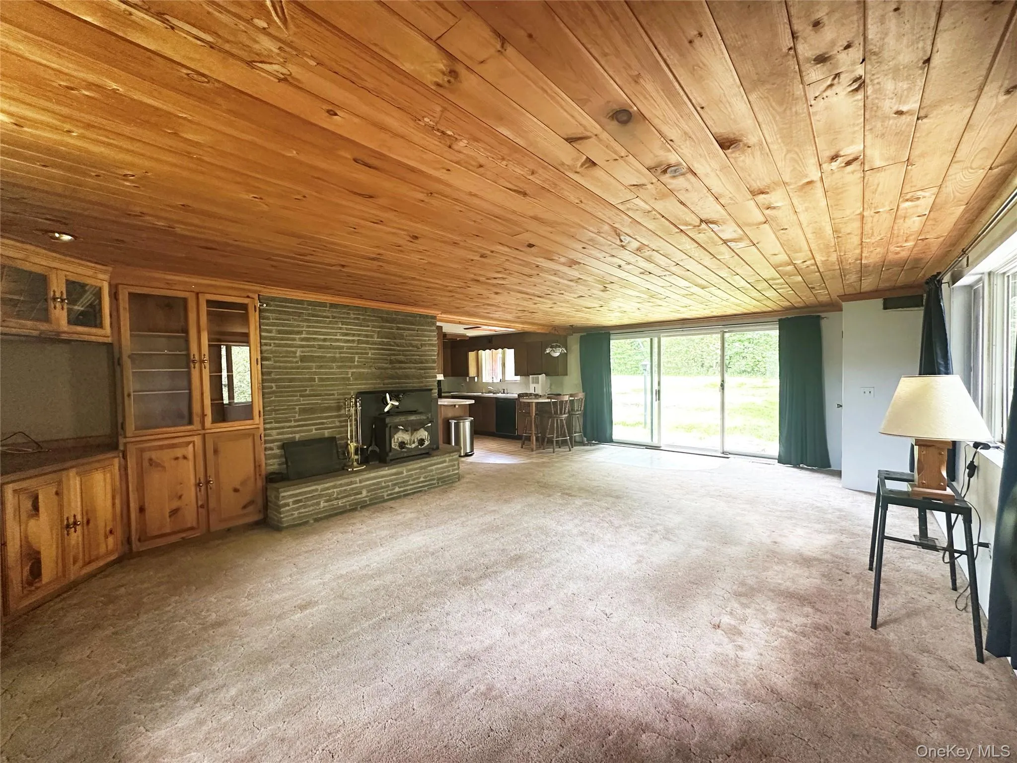 Wide-angle view of the open-concept living and dining area highlighting the rustic wood ceilings, fireplace centerpiece, and expansive layout. Wide-angle view of the open-concept living and dining area highlighting the rustic wood ceilings, fireplace centerpiece, and expansive layout.