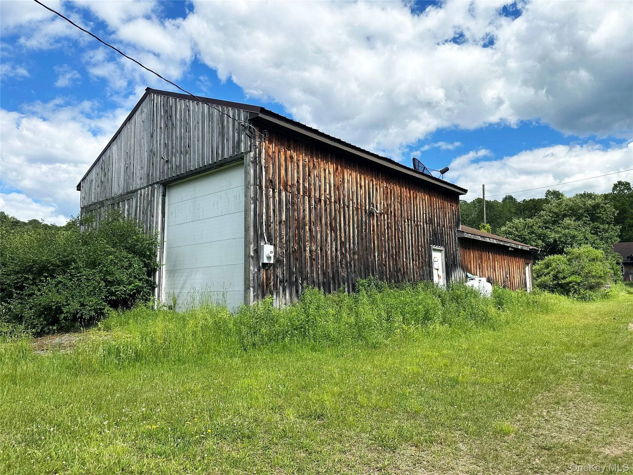 Large barn-style outbuilding with oversized garage door, high ceilings, and flexible space for garage, storage, equipment, workshop, or hobby use. Large barn-style outbuilding with oversized garage door, high ceilings, and flexible space for garage, storage, equipment, workshop, or hobby use.