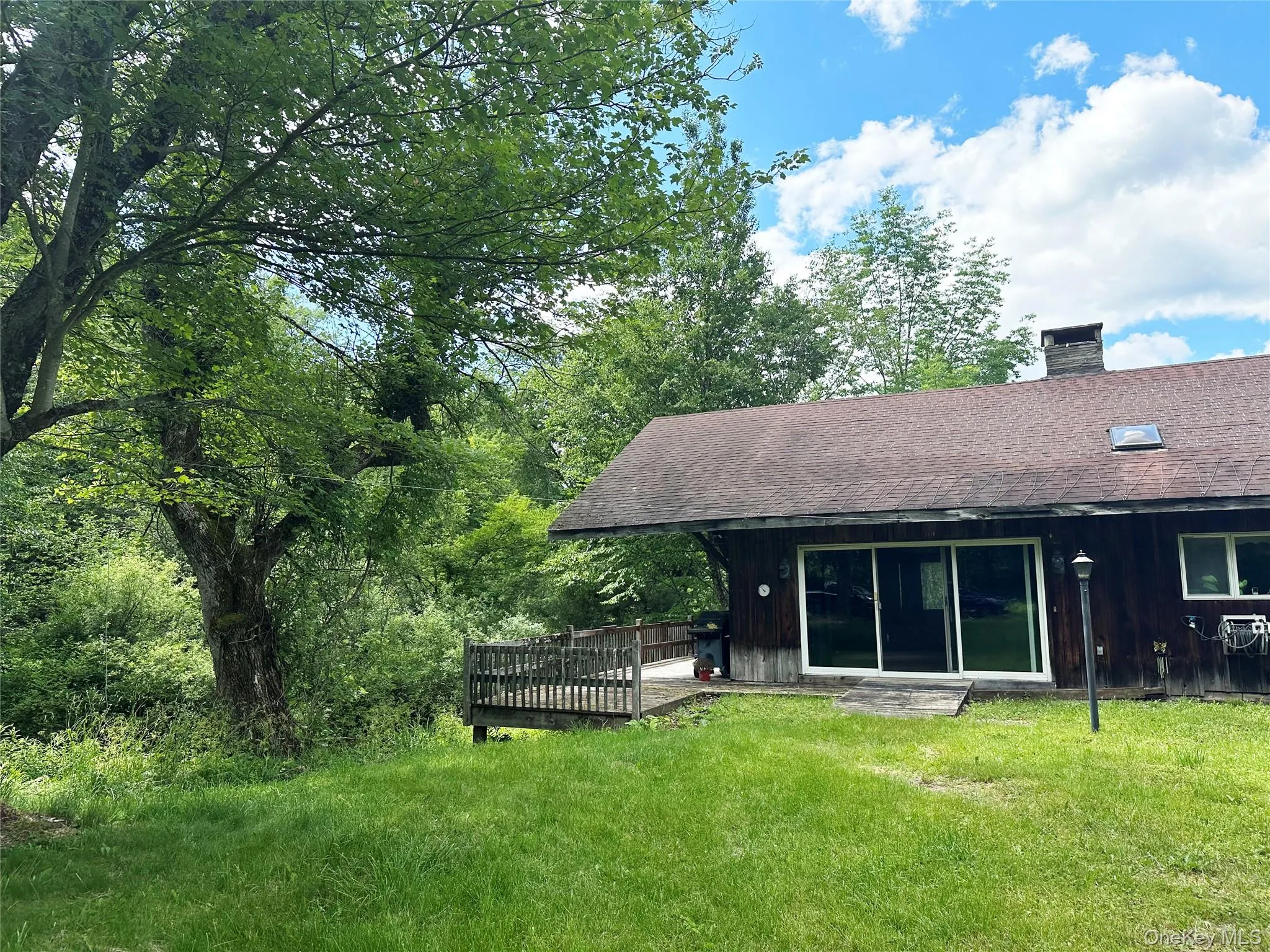 Front exterior of the home with deck overlooking Trout Brook, surrounded by mature trees and tranquil waterfront scenery. Front exterior of the home with deck overlooking Trout Brook, surrounded by mature trees and tranquil waterfront scenery.