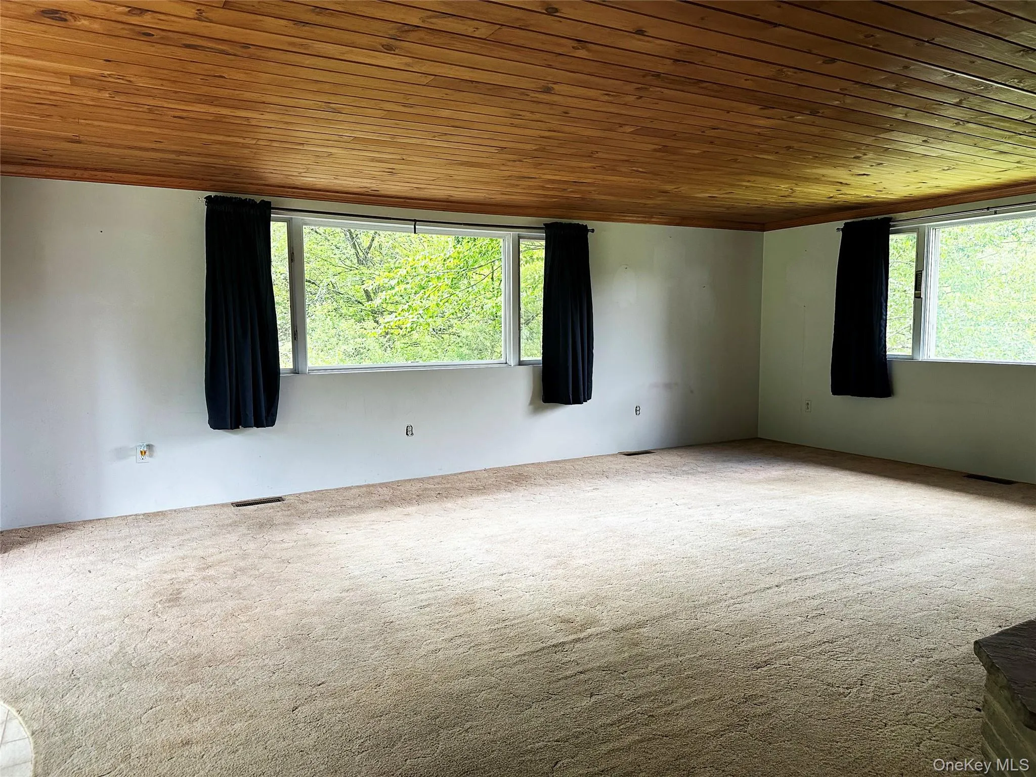 Expansive living area with oversized windows overlooking the surrounding greenery, complemented by original wood ceilings and rustic finishes throughout. Expansive living area with oversized windows overlooking the surrounding greenery, complemented by original wood ceilings and rustic finishes throughout.
