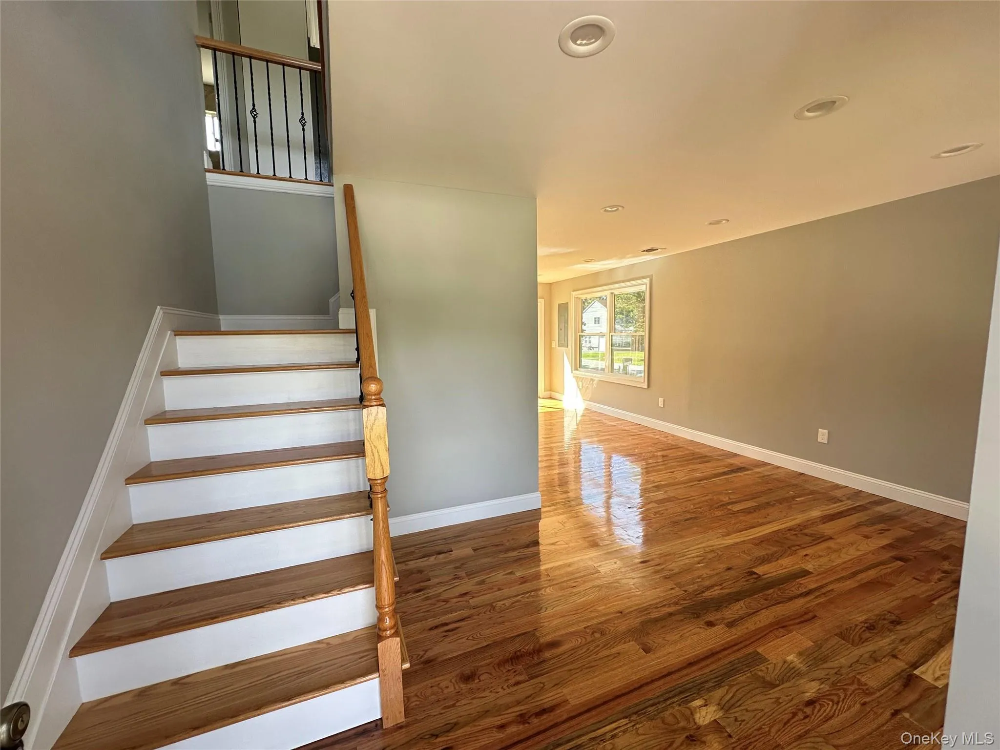 Hardwood flooring spans the open-concept living area, featuring recessed lighting and white baseboards Hardwood flooring spans the open-concept living area, featuring recessed lighting and white baseboards