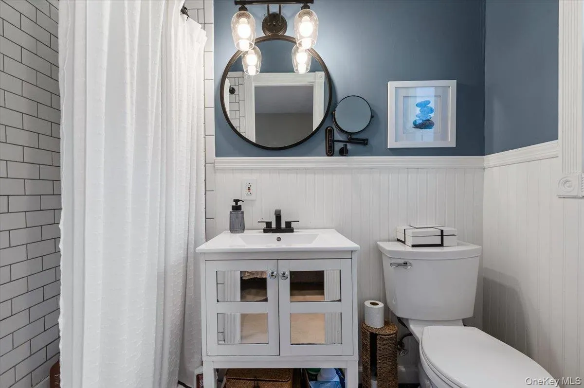 Bathroom featuring a white vanity with integrated sink, black faucet, and mirrored cabinet doors Bathroom featuring a white vanity with integrated sink, black faucet, and mirrored cabinet doors