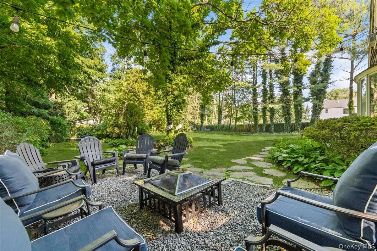 Spacious backyard featuring a stone paver path, mature trees, and string lighting Spacious backyard featuring a stone paver path, mature trees, and string lighting