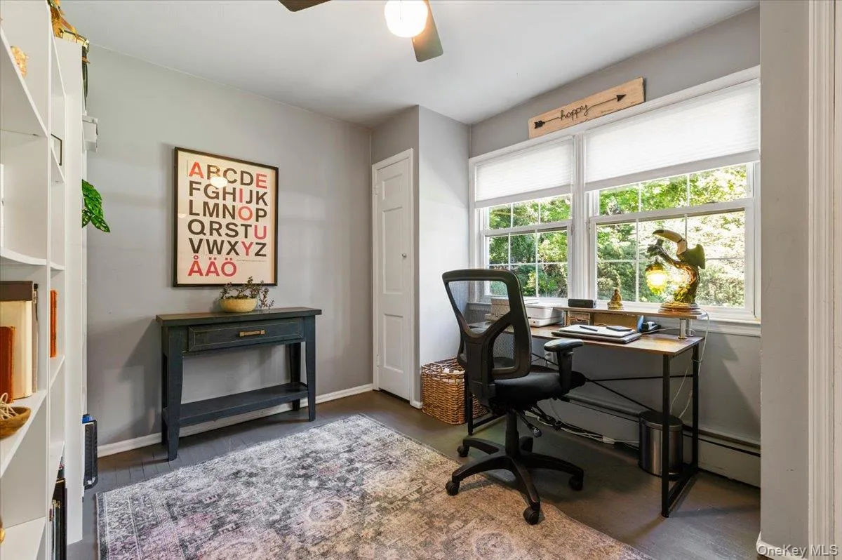 Dedicated room featuring dark wood-finish flooring, white built-in shelving, and light gray wall paint Dedicated room featuring dark wood-finish flooring, white built-in shelving, and light gray wall paint