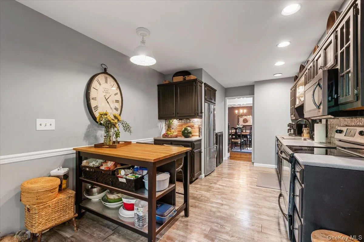 Galley kitchen with dark wood-finish cabinetry, stainless steel appliances, and wood-finish flooring Galley kitchen with dark wood-finish cabinetry, stainless steel appliances, and wood-finish flooring