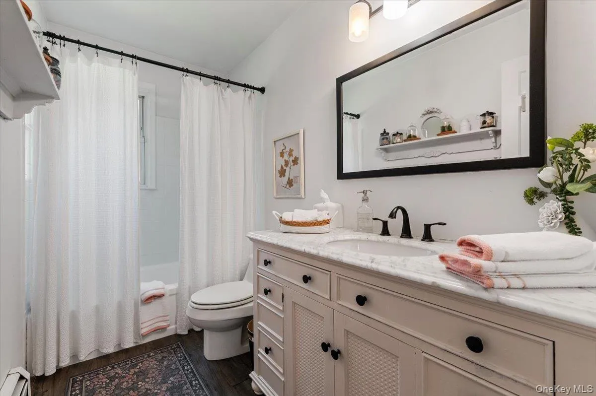 Bathroom featuring a single vanity with a stone countertop, an undermount sink, and a black framed mirror Bathroom featuring a single vanity with a stone countertop, an undermount sink, and a black framed mirror