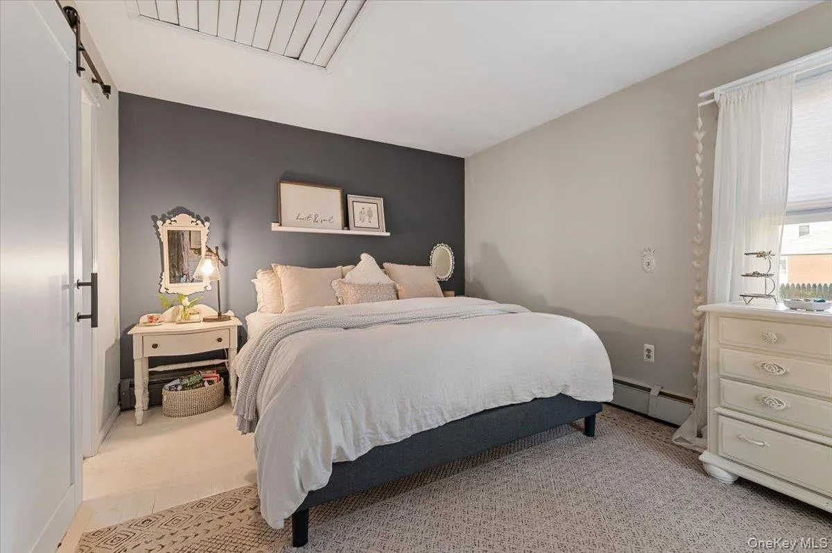 Bedroom featuring a dark accent wall, light neutral wall color, and a window with white blinds Bedroom featuring a dark accent wall, light neutral wall color, and a window with white blinds