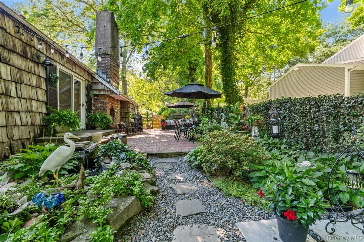 Spacious outdoor patio area featuring a brick paver surface, mature trees, and string lighting Spacious outdoor patio area featuring a brick paver surface, mature trees, and string lighting