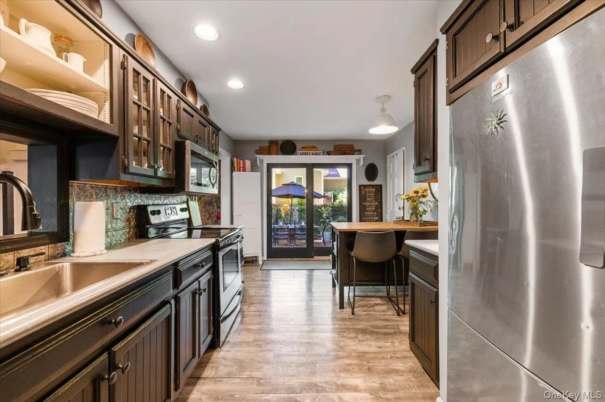 Kitchen featuring wood-finish flooring, dark cabinetry, recessed lighting, and stainless steel appliances Kitchen featuring wood-finish flooring, dark cabinetry, recessed lighting, and stainless steel appliances