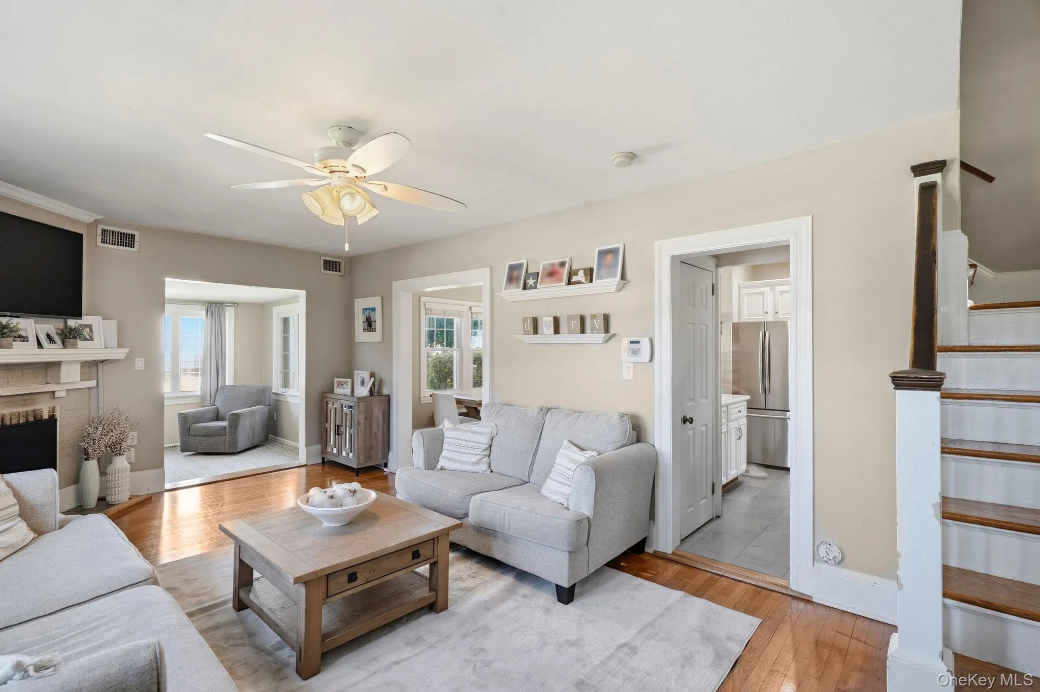 Living room with hardwood floors and fireplace open to a separate sunroom, dining room and kitchen Living room with hardwood floors and fireplace open to a separate sunroom, dining room and kitchen