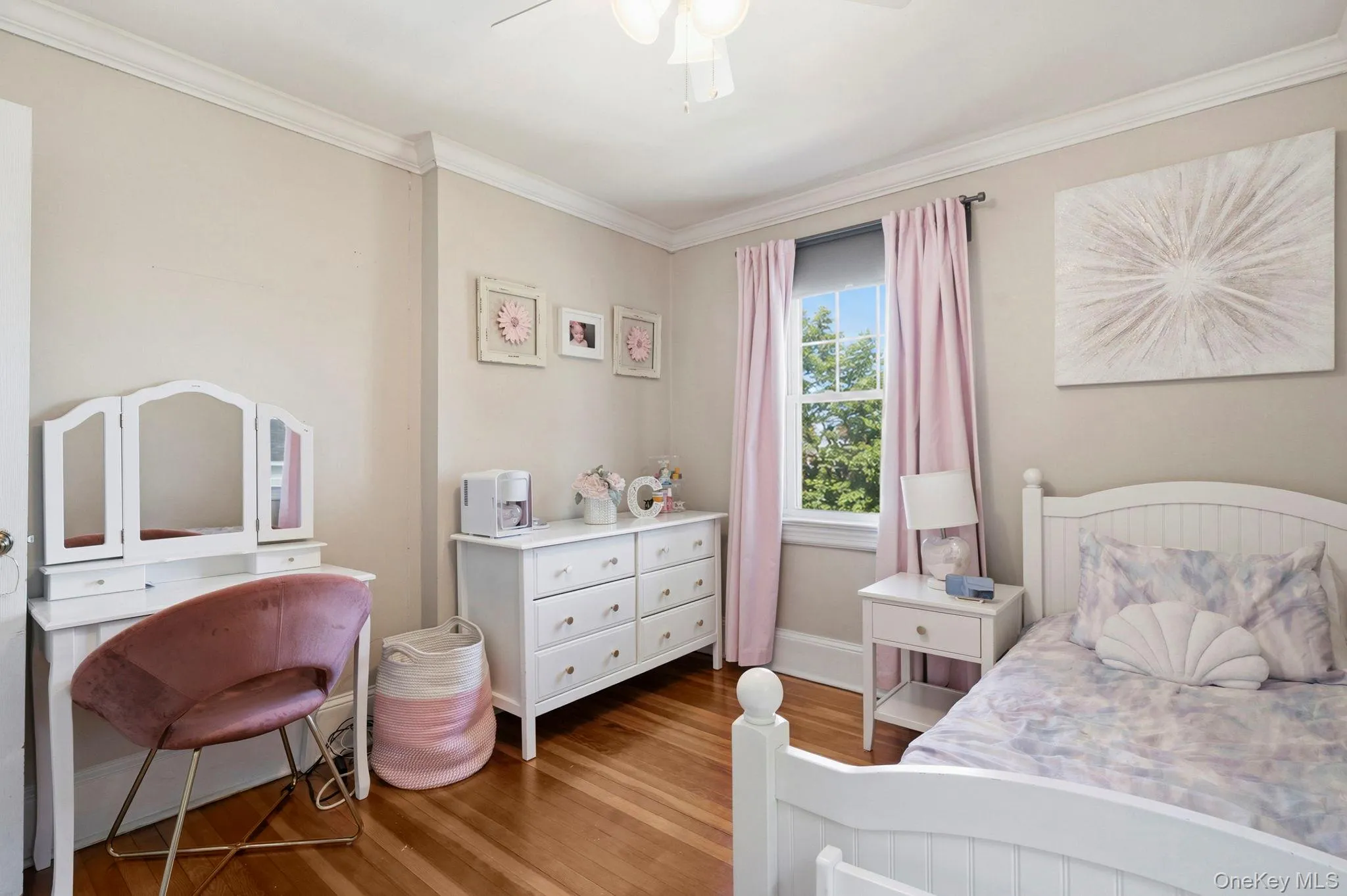 Bedroom featuring wood-finish flooring, white crown molding, and a double-hung window Bedroom featuring wood-finish flooring, white crown molding, and a double-hung window
