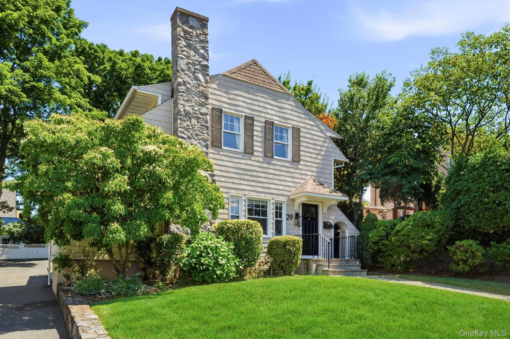 Traditional-style residence featuring a stone chimney, shingle siding, and a gabled roof Traditional-style residence featuring a stone chimney, shingle siding, and a gabled roof