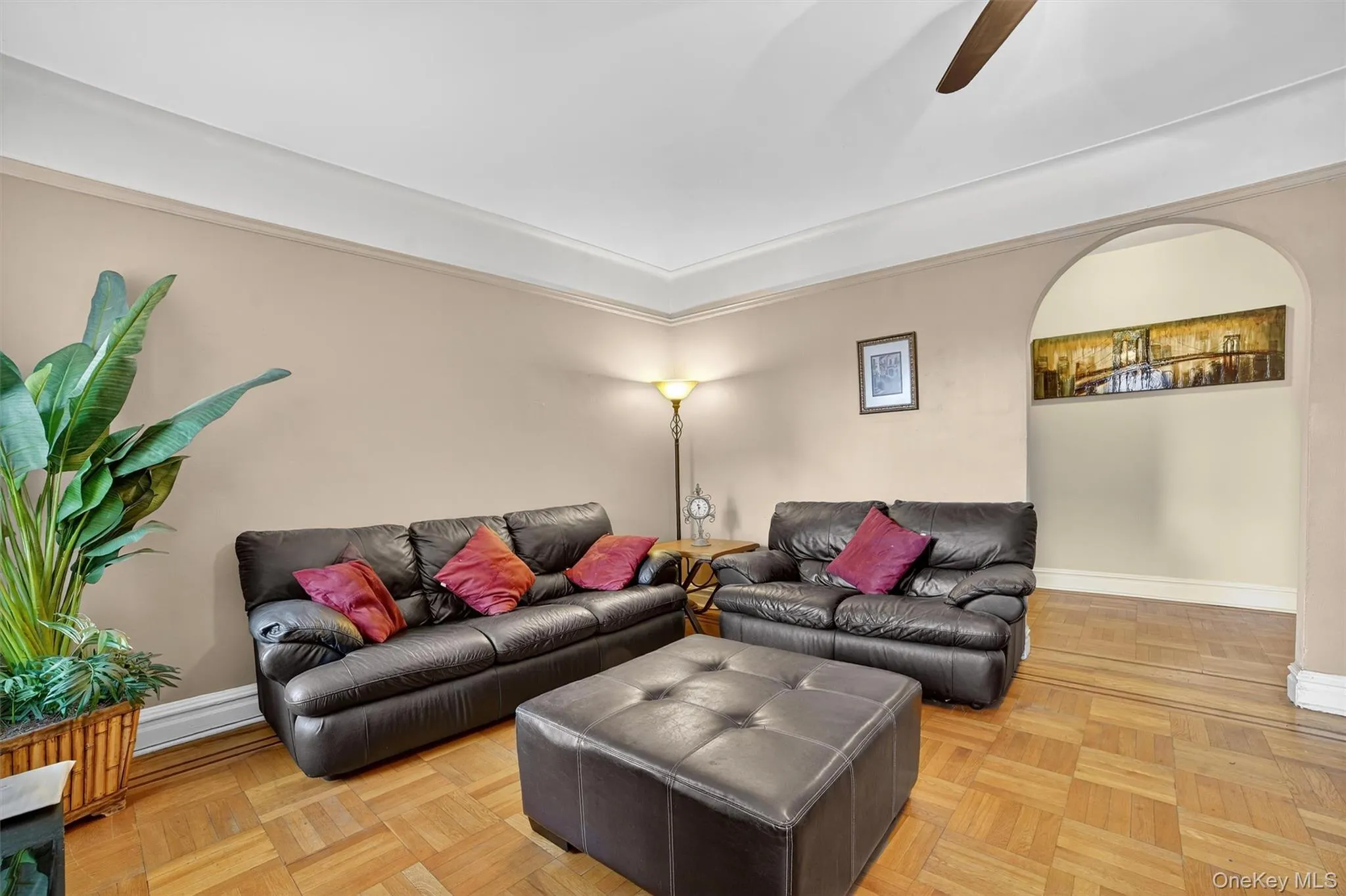 Living room featuring arched walkways, ceiling fan, and ornamental molding Living room featuring arched walkways, ceiling fan, and ornamental molding