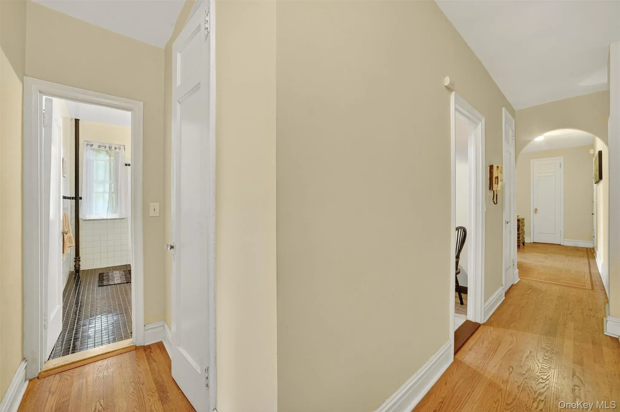Hallway featuring light wood-type flooring and arched walkways Hallway featuring light wood-type flooring and arched walkways