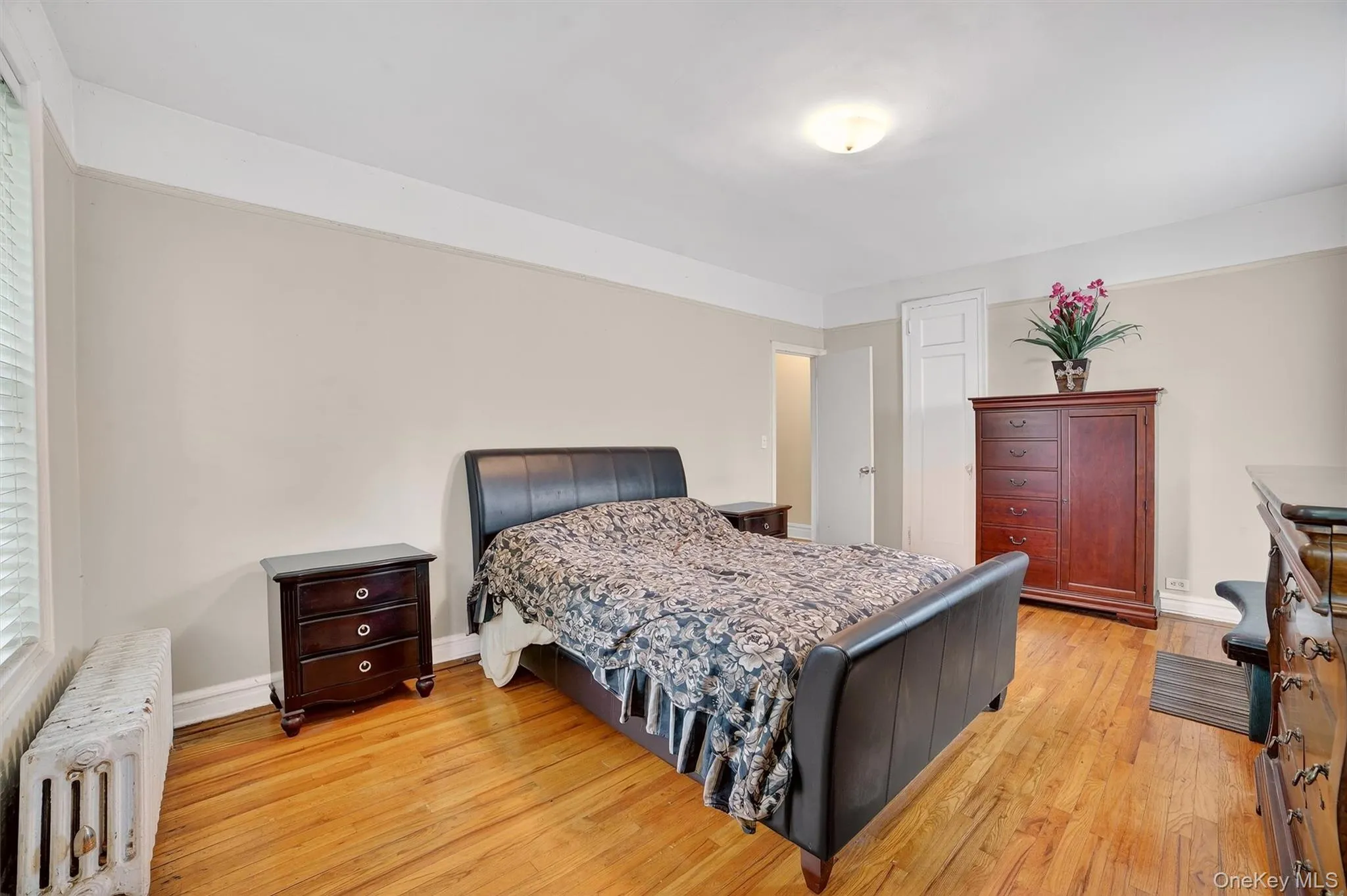 Bedroom featuring radiator heating unit and light wood finished floors Bedroom featuring radiator heating unit and light wood finished floors