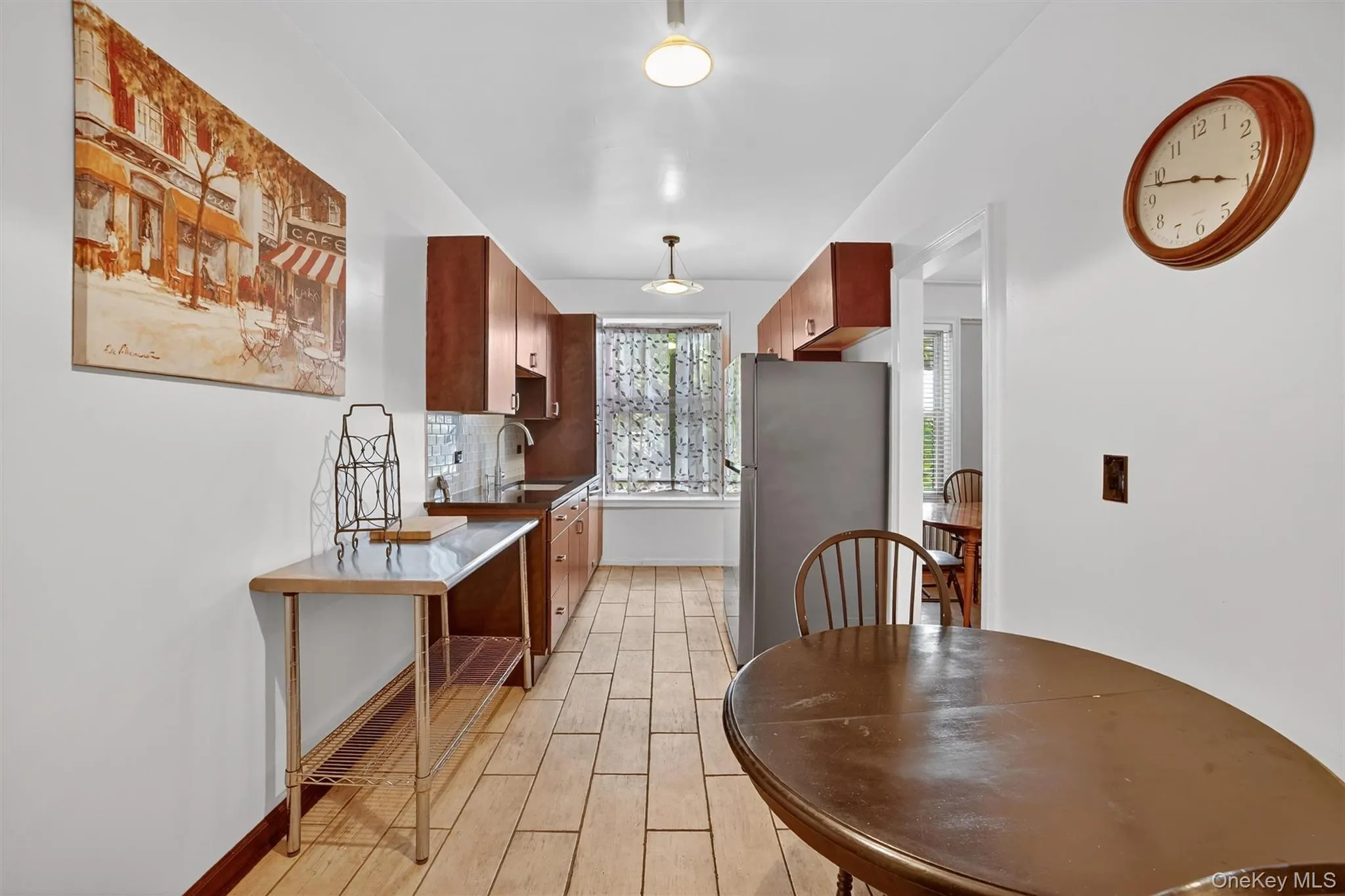 Kitchen featuring brown cabinetry, freestanding refrigerator, wood tiled floors, and decorative backsplash Kitchen featuring brown cabinetry, freestanding refrigerator, wood tiled floors, and decorative backsplash