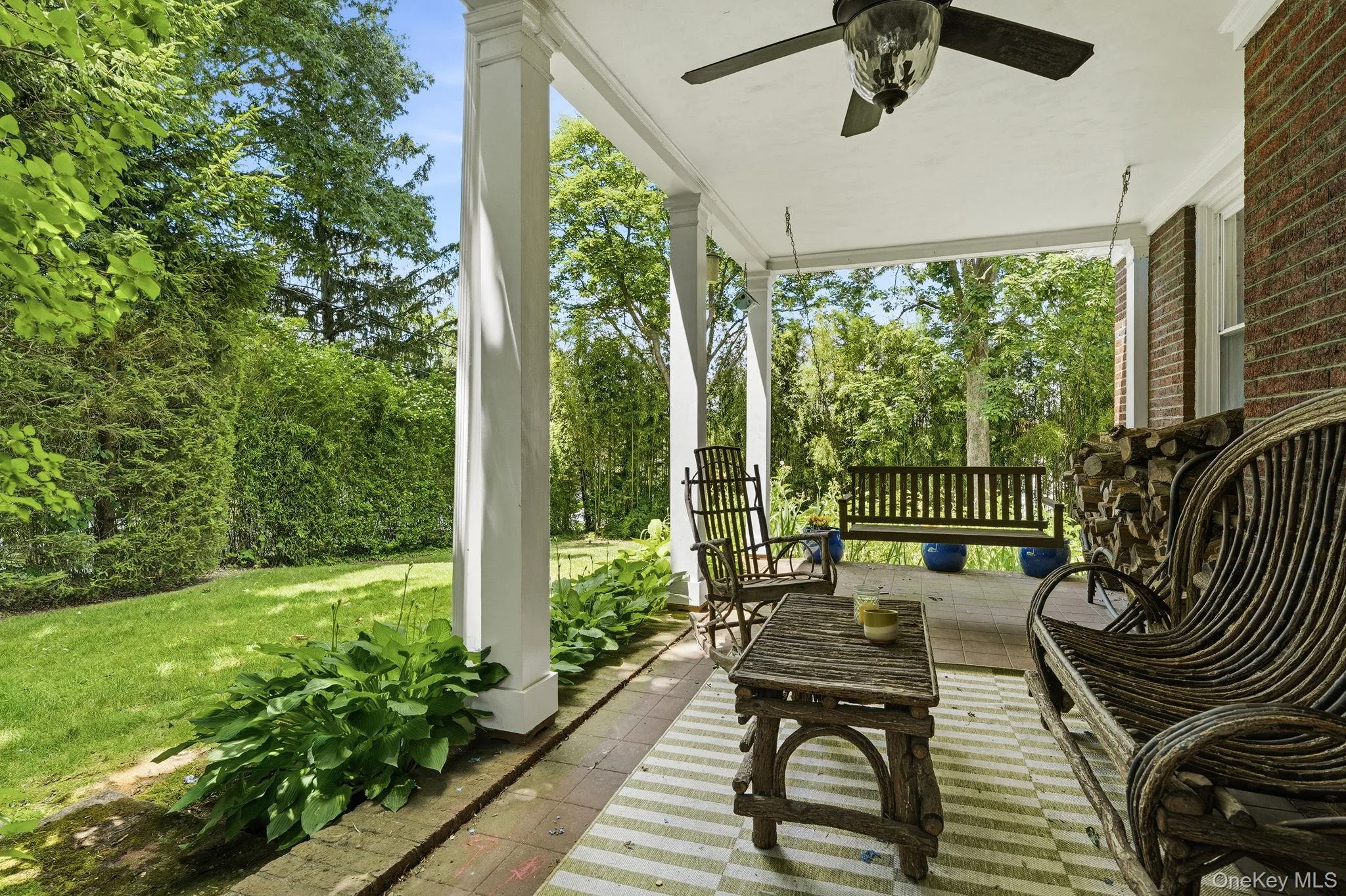 A peaceful covered porch surrounded by mature landscaping. A peaceful covered porch surrounded by mature landscaping.