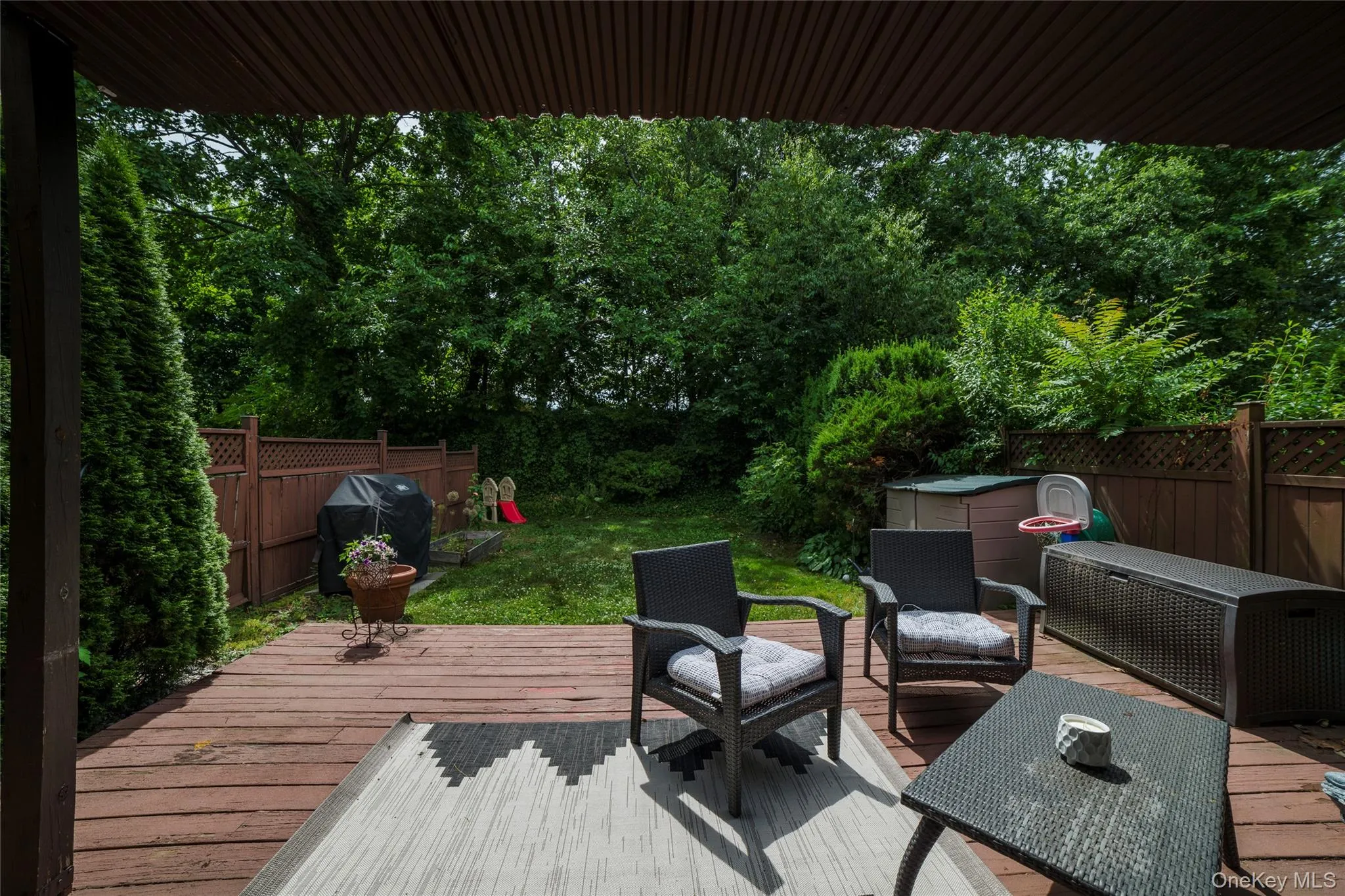 Expansive outdoor deck accessing private yard and a partial overhead covering Expansive outdoor deck accessing private yard and a partial overhead covering