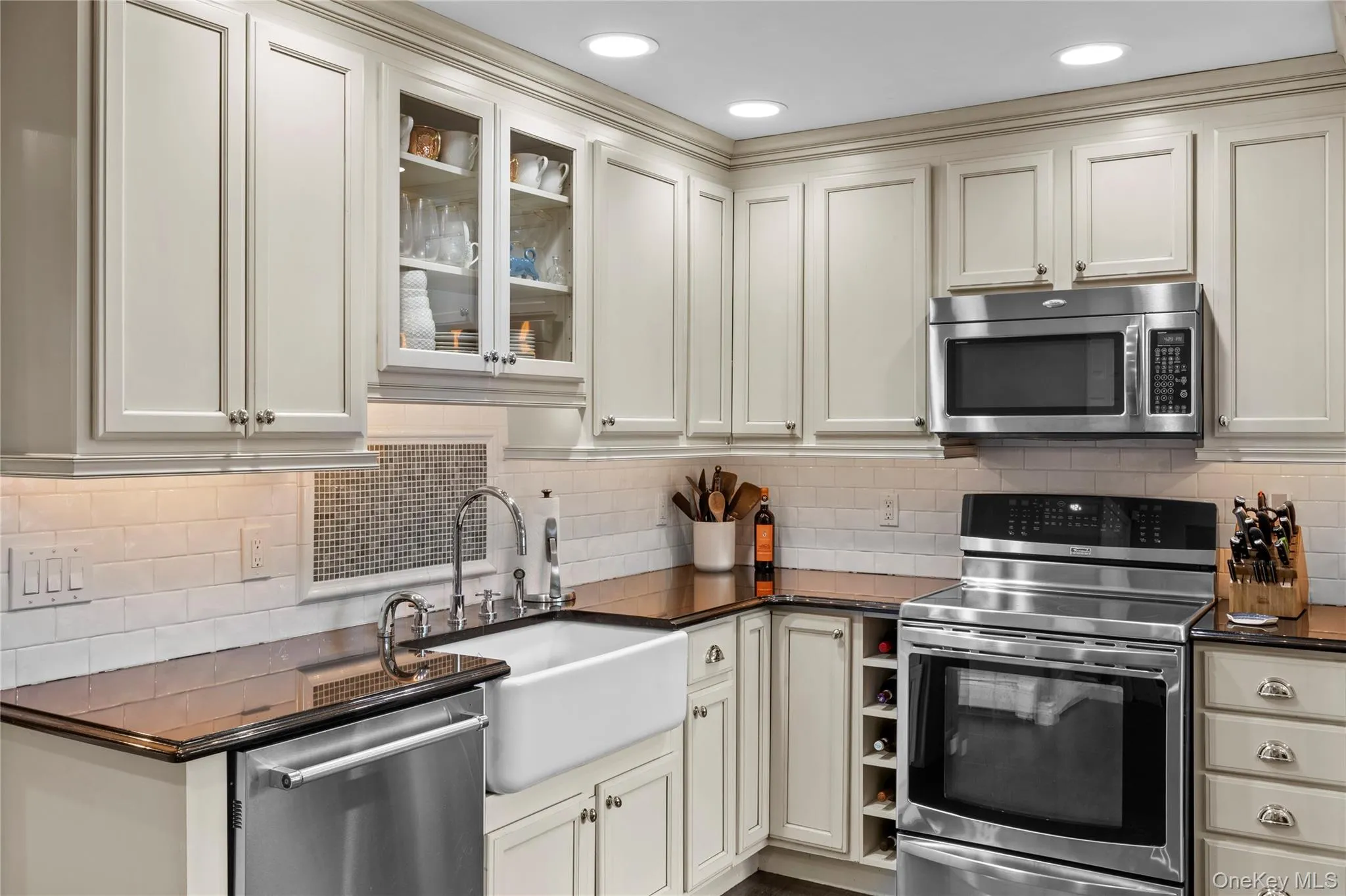 Showcasing the tile backsplash, farm sink and white cabinetry Showcasing the tile backsplash, farm sink and white cabinetry