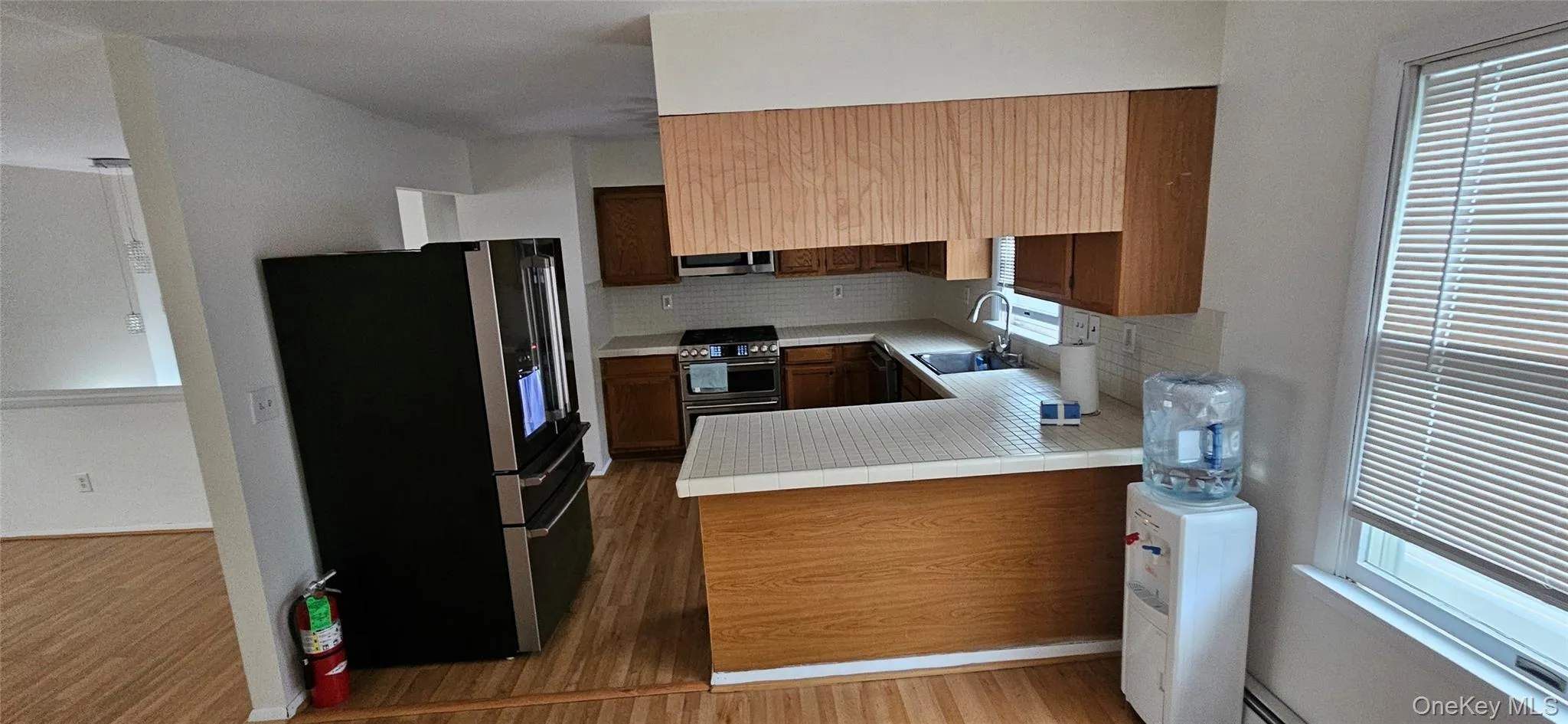 Kitchen featuring wood-finish flooring, wood cabinetry, white tile countertops, and a stainless steel range oven Kitchen featuring wood-finish flooring, wood cabinetry, white tile countertops, and a stainless steel range oven