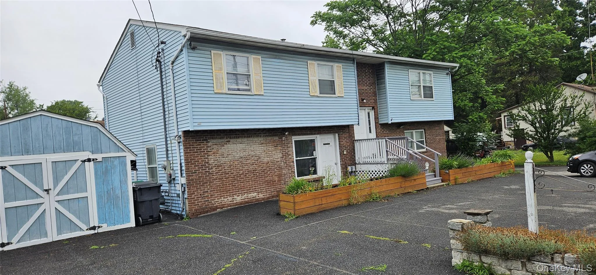 Light blue siding exterior with a brick lower level, featuring a white main entry door with a multi-level porch Light blue siding exterior with a brick lower level, featuring a white main entry door with a multi-level porch