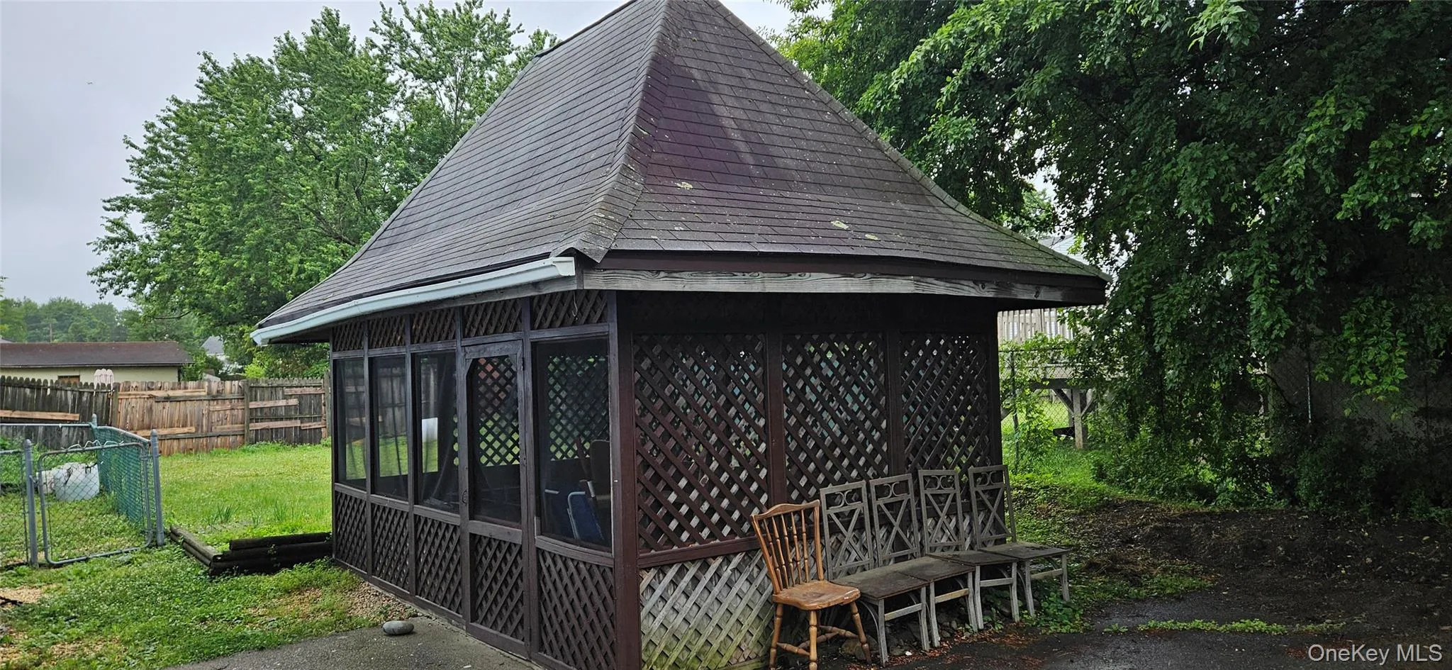 Wood-framed gazebo featuring a hip roof with asphalt shingles, lattice paneling, and screened windows Wood-framed gazebo featuring a hip roof with asphalt shingles, lattice paneling, and screened windows