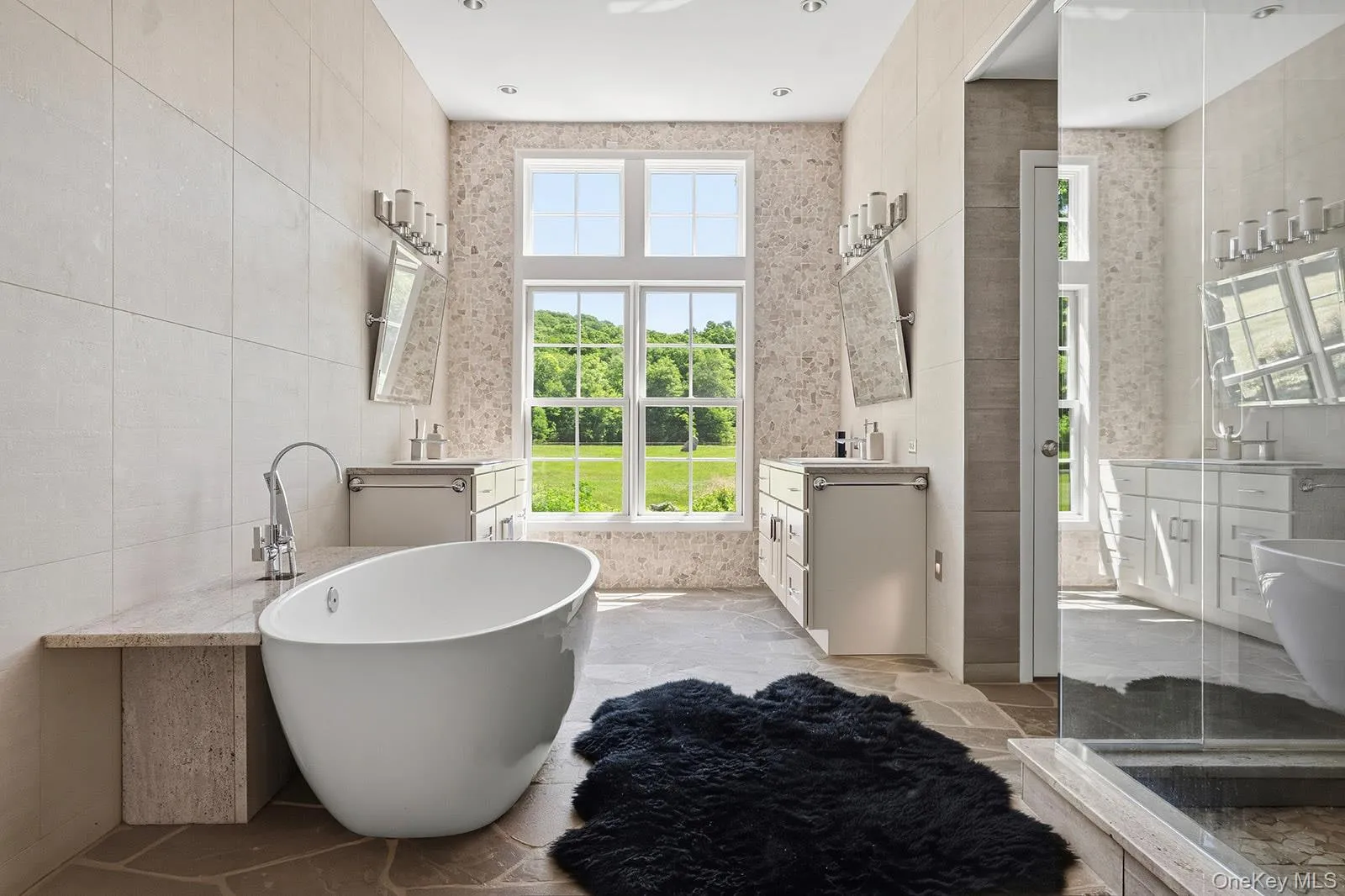 Primary bathroom with twin vanities, soaking tub, large glass shower with dual rain shower heads, separate lavatory and radiant heated bluestone floors Primary bathroom with twin vanities, soaking tub, large glass shower with dual rain shower heads, separate lavatory and radiant heated bluestone floors