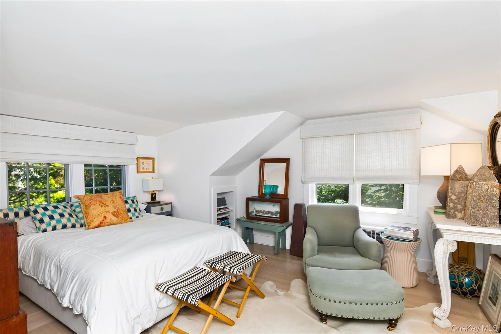 Bright interior featuring light wood-finish flooring and multiple windows with white blinds Bright interior featuring light wood-finish flooring and multiple windows with white blinds