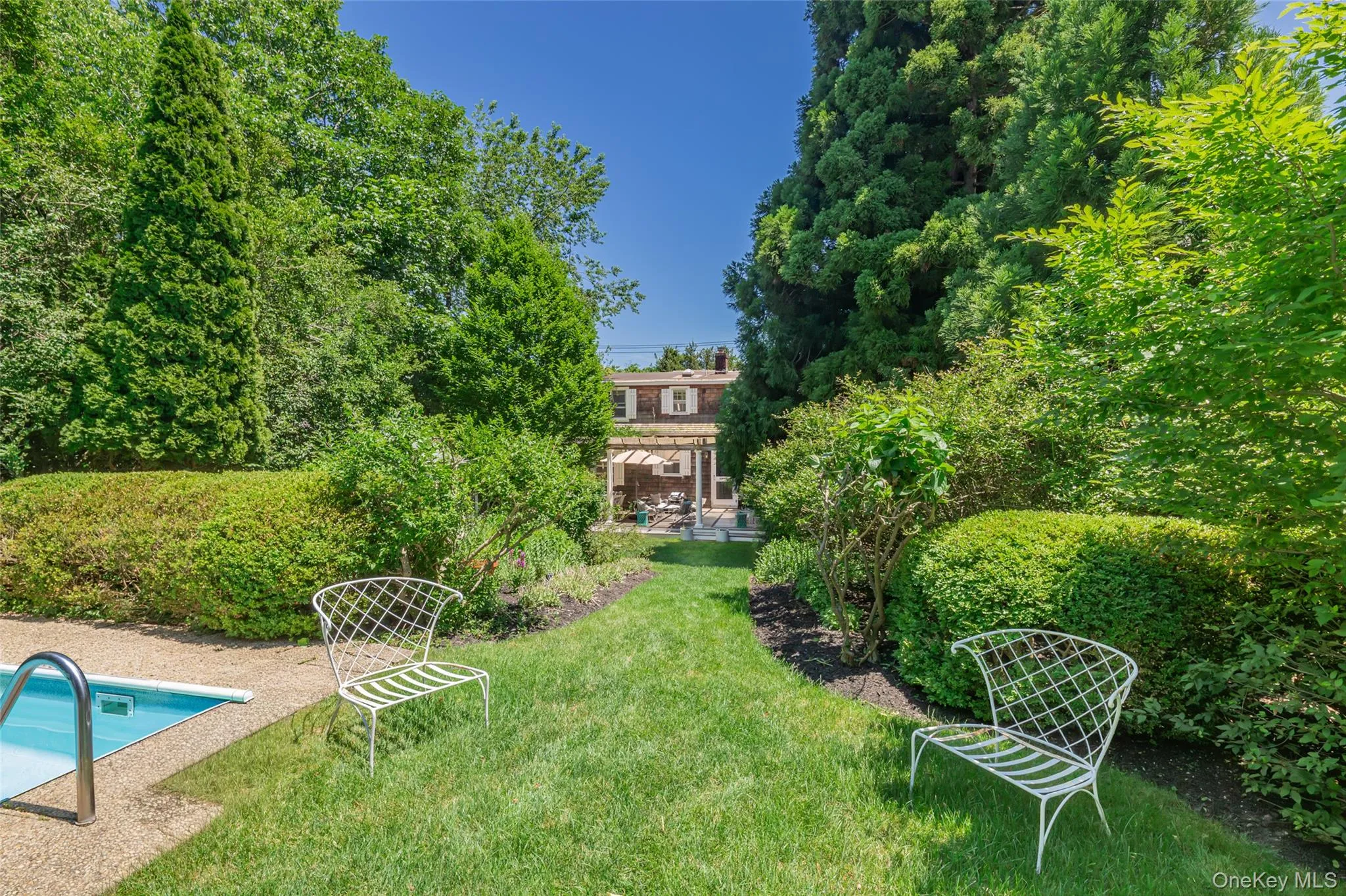 Expansive backyard featuring a manicured lawn, established shrubbery, and mature trees Expansive backyard featuring a manicured lawn, established shrubbery, and mature trees