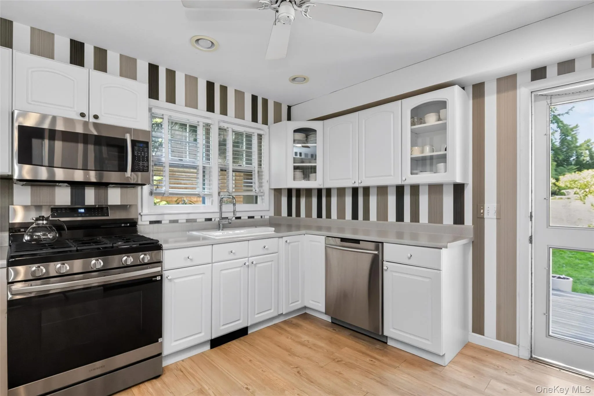 Kitchen featuring wood-finish flooring, white cabinetry, and access to the rear dining pavilion Kitchen featuring wood-finish flooring, white cabinetry, and access to the rear dining pavilion
