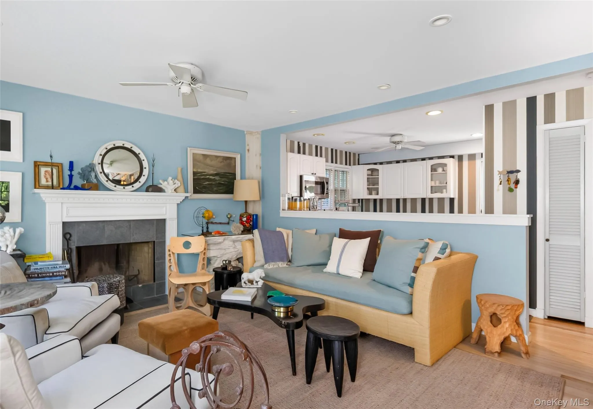 Living area featuring a fireplace with a stone surround and a white mantel, light blue walls, and Hampton decor Living area featuring a fireplace with a stone surround and a white mantel, light blue walls, and Hampton decor