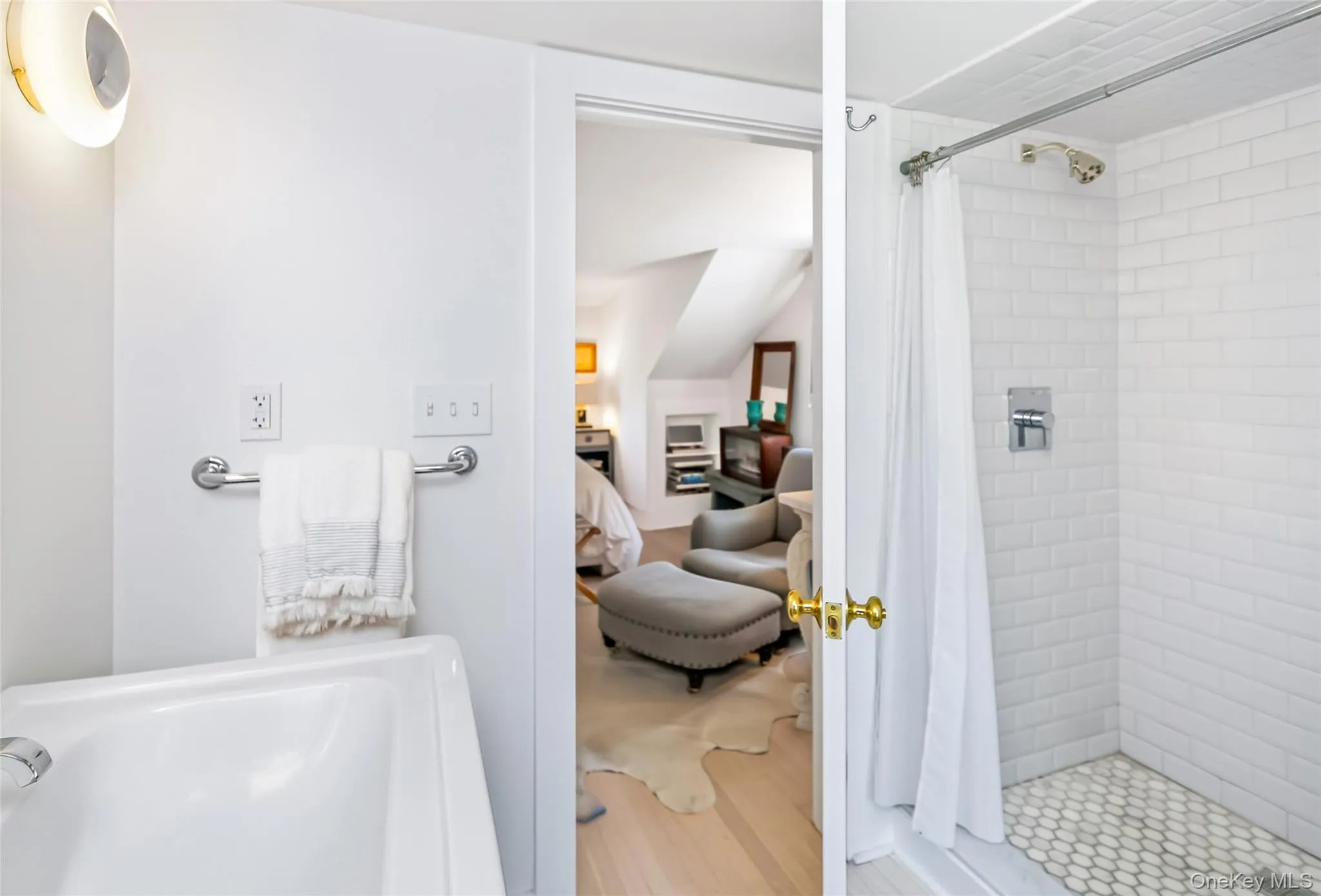 Primary bathroom featuring a white subway tile shower with hexagonal tile flooring, a white porcelain tub, and a chrome towel bar Primary bathroom featuring a white subway tile shower with hexagonal tile flooring, a white porcelain tub, and a chrome towel bar