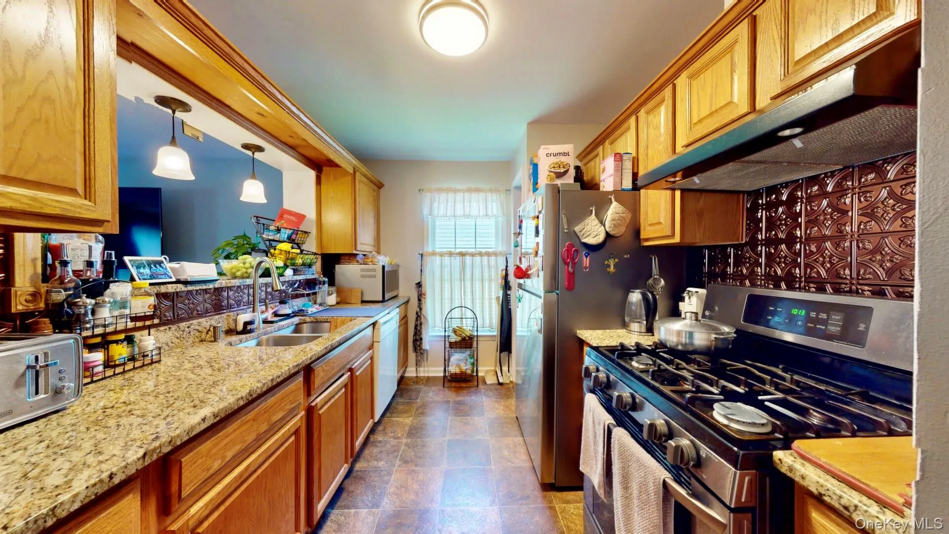 Kitchen with stainless steel gas range oven, a sink, under cabinet range hood, white dishwasher, and light stone counters Kitchen with stainless steel gas range oven, a sink, under cabinet range hood, white dishwasher, and light stone counters