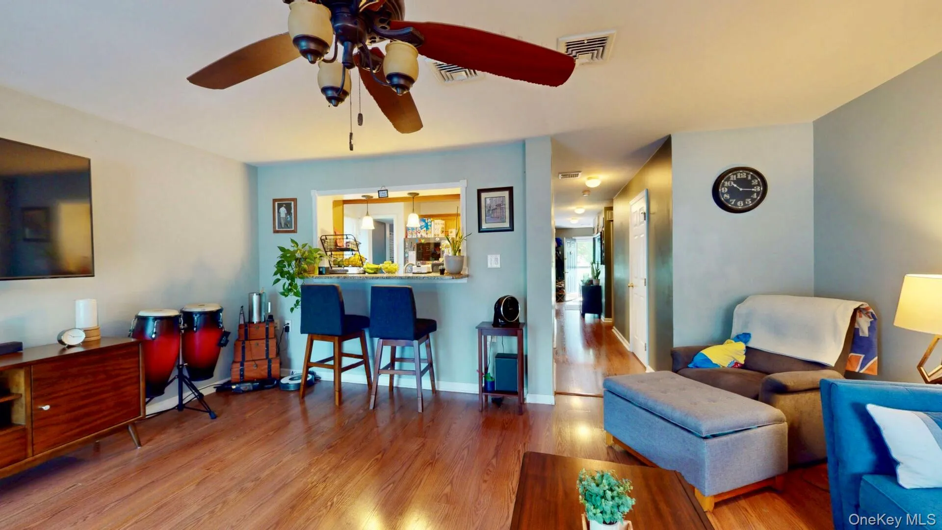 Living room featuring wood finished floors, a ceiling fan, and baseboards Living room featuring wood finished floors, a ceiling fan, and baseboards