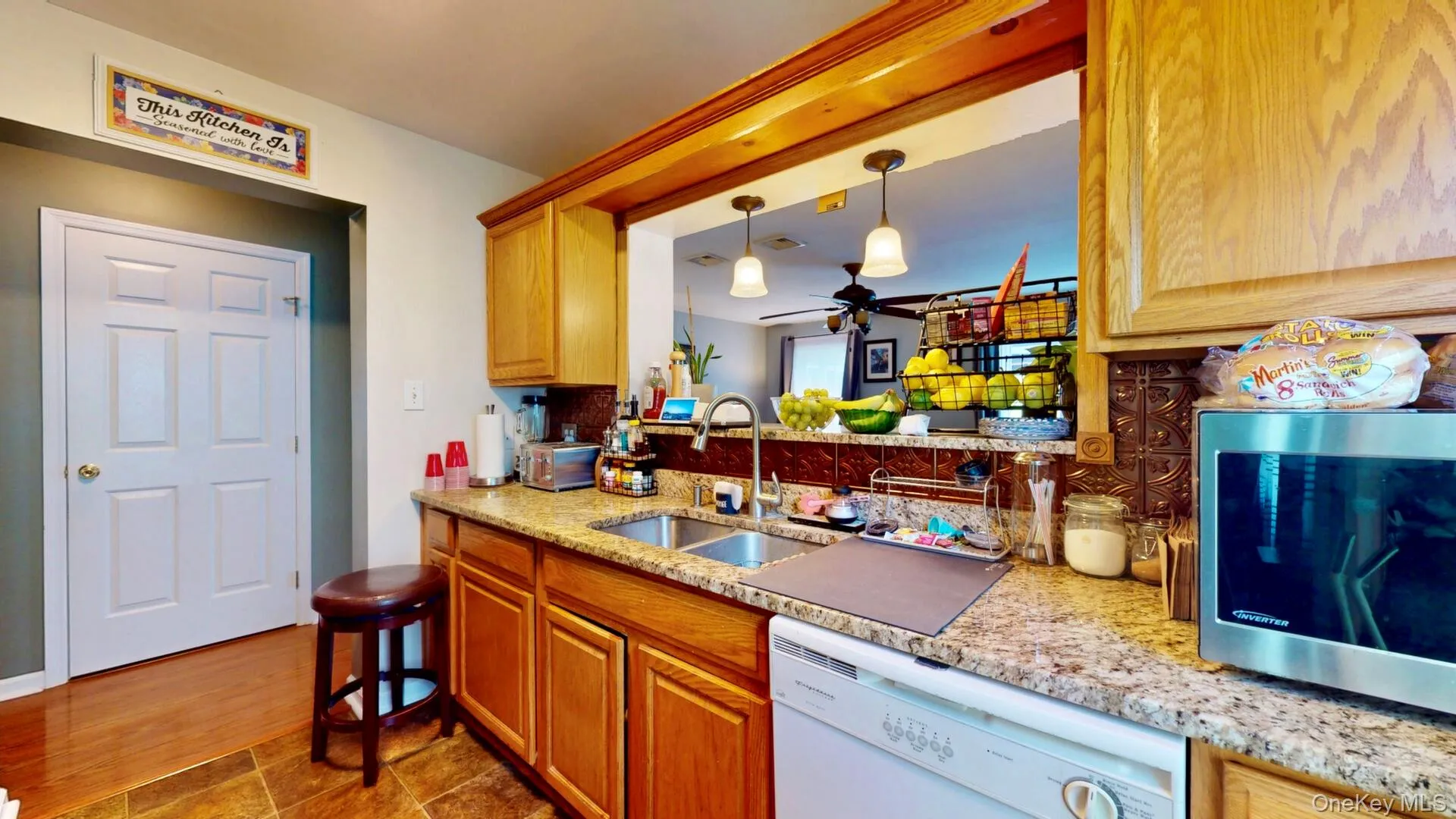 Kitchen with dishwasher, stainless steel microwave, a sink, ceiling fan, and hanging light fixtures Kitchen with dishwasher, stainless steel microwave, a sink, ceiling fan, and hanging light fixtures