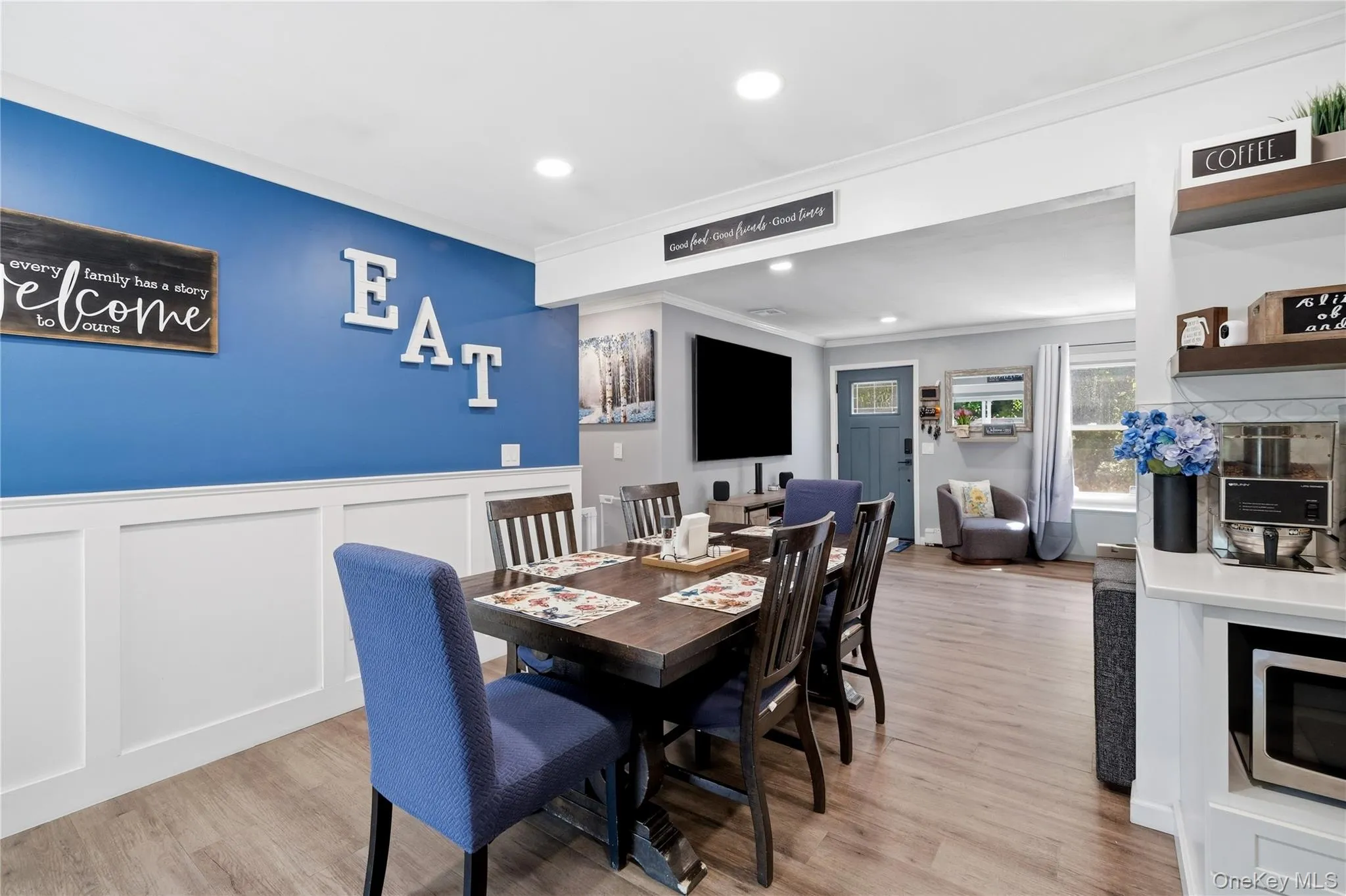Dining area with wood-finish flooring, recessed lighting, and a blue accent wall featuring white wainscoting Dining area with wood-finish flooring, recessed lighting, and a blue accent wall featuring white wainscoting