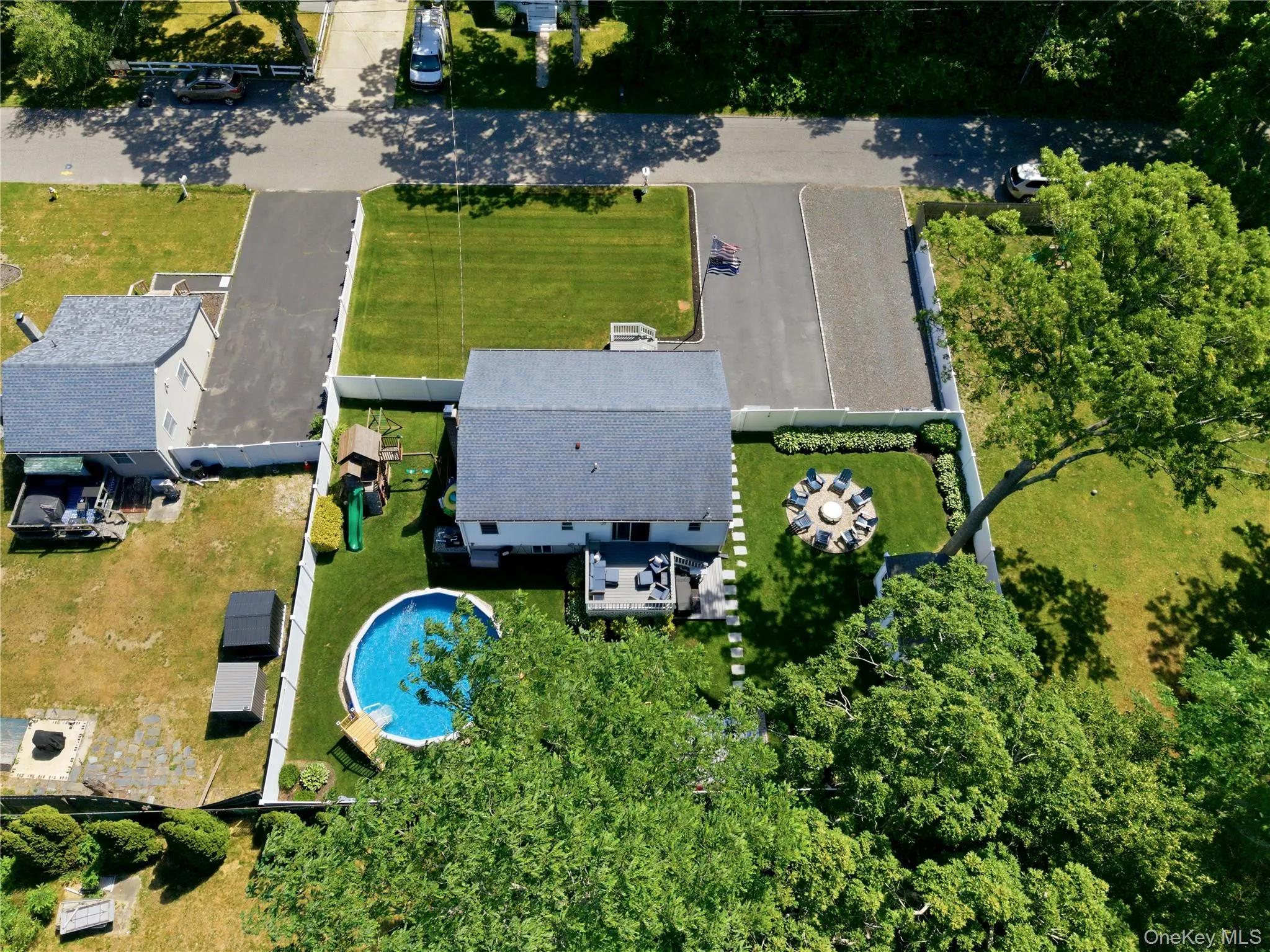 Rear exterior featuring a deck, an above-ground pool, a fenced yard, and a paved patio area Rear exterior featuring a deck, an above-ground pool, a fenced yard, and a paved patio area