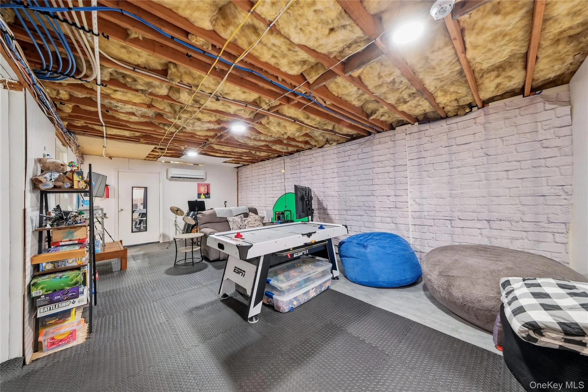 Finished basement space featuring lighting, and a white brick-patterned accent wall Finished basement space featuring lighting, and a white brick-patterned accent wall