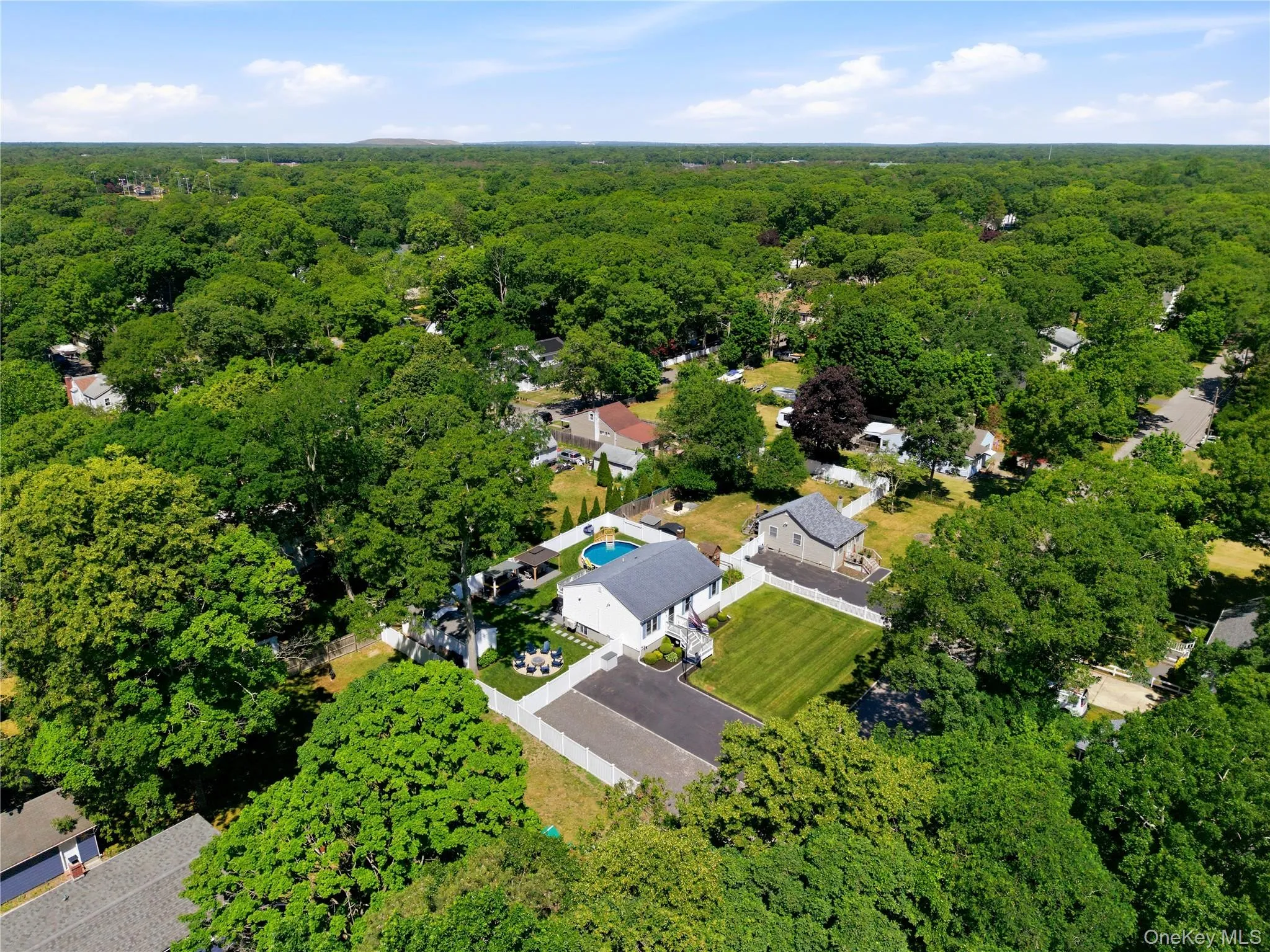 Expansive property featuring a circular swimming pool, manicured lawn, paved driveway, and perimeter fencing Expansive property featuring a circular swimming pool, manicured lawn, paved driveway, and perimeter fencing