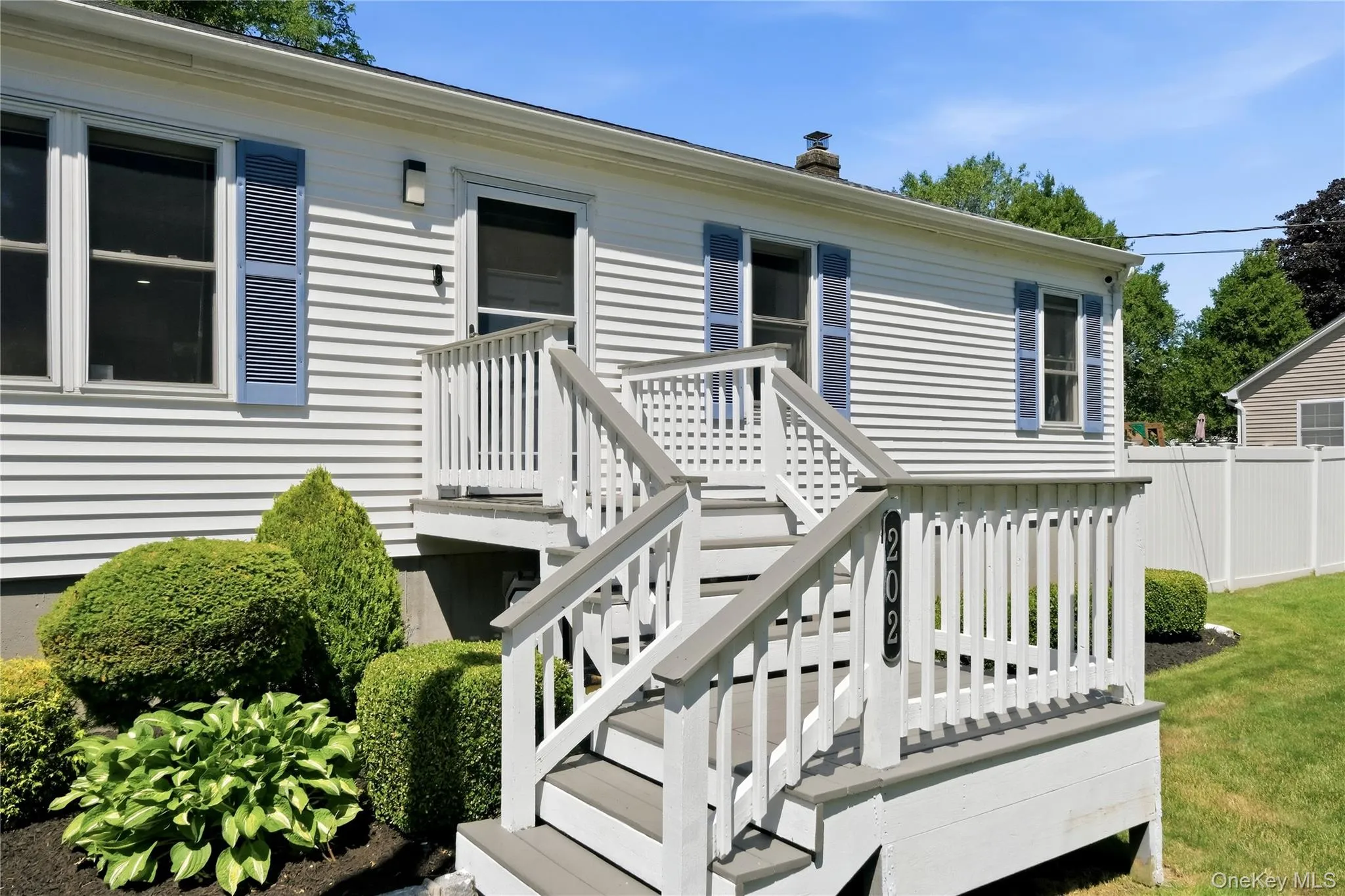 Exterior siding with blue louvered shutters, featuring a multi-level deck entry with composite decking and white railings Exterior siding with blue louvered shutters, featuring a multi-level deck entry with composite decking and white railings