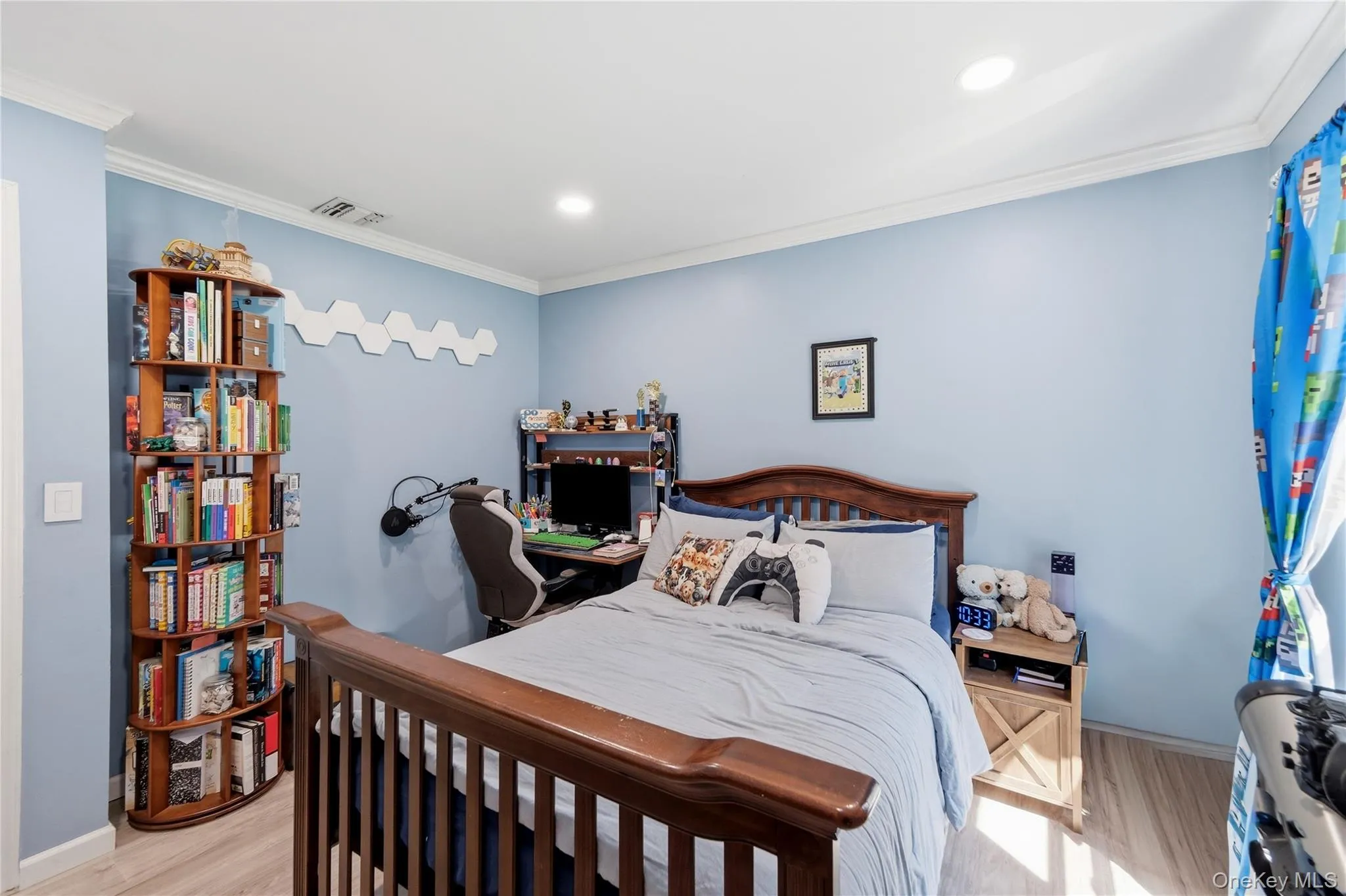 Recessed lighting illuminates this room featuring wood-finish flooring, light blue wall paint, and white crown molding Recessed lighting illuminates this room featuring wood-finish flooring, light blue wall paint, and white crown molding
